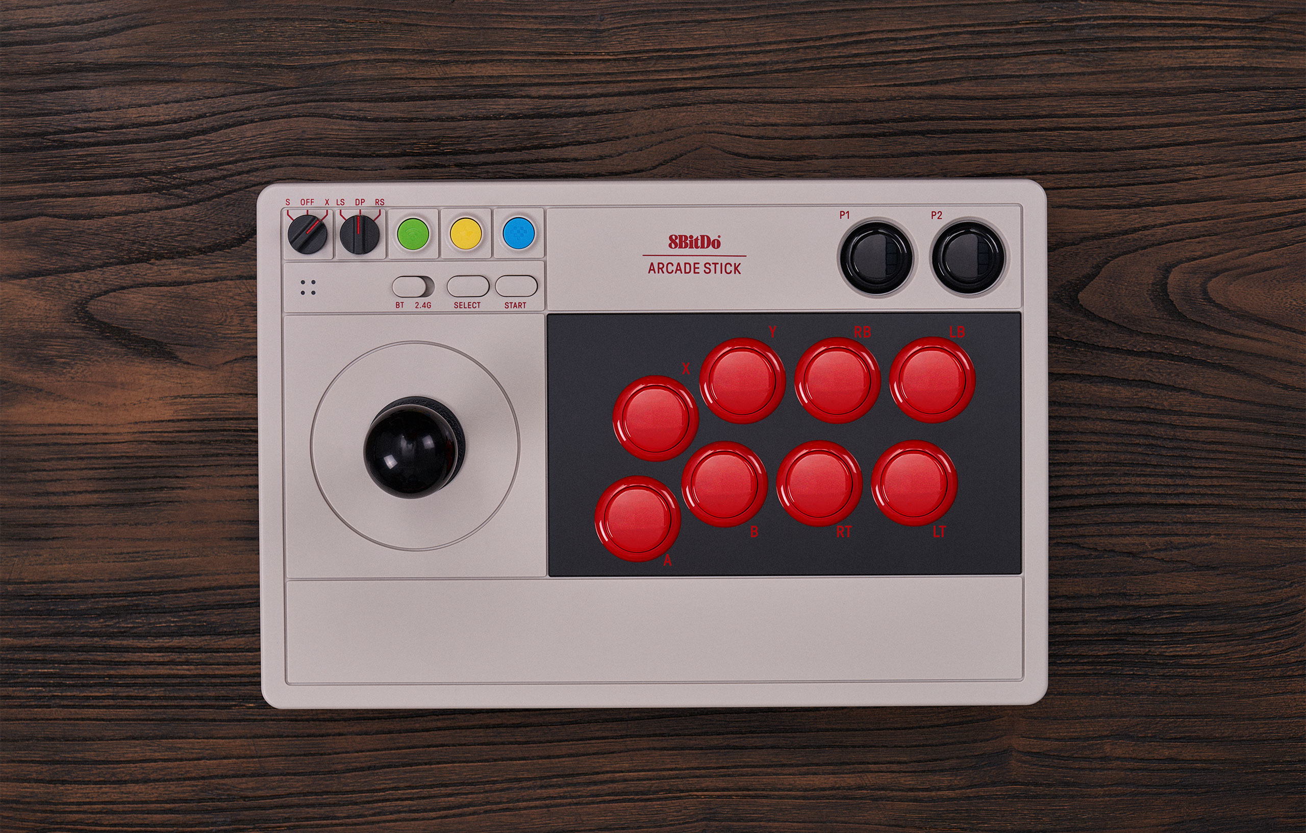 Un arcade stick 8BitDo, bianco e rosso, su una superficie di legno. Ha un joystick e pulsanti rossi.