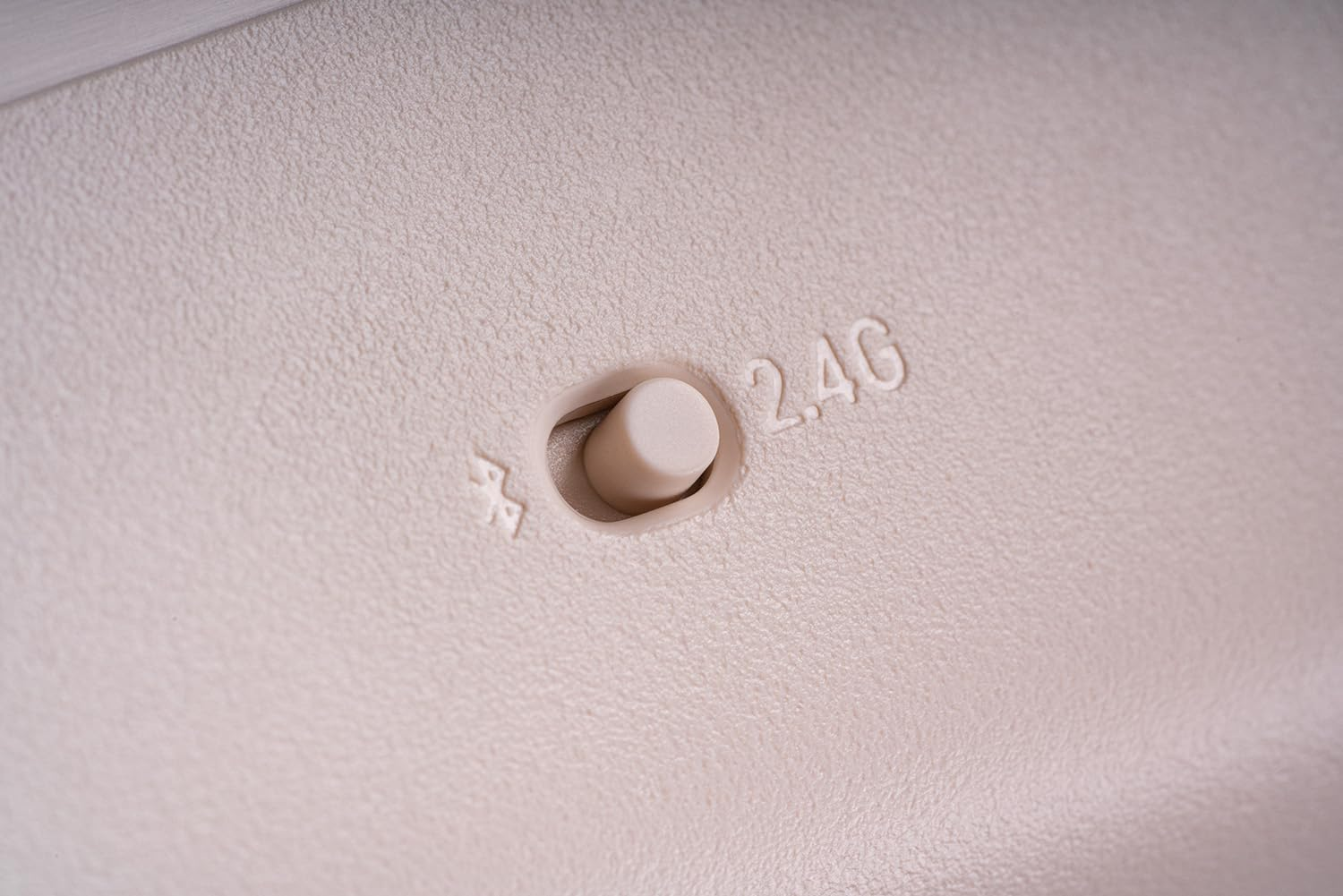 Primer plano de una superficie beige con un interruptor con símbolos de Bluetooth y 2.4G.