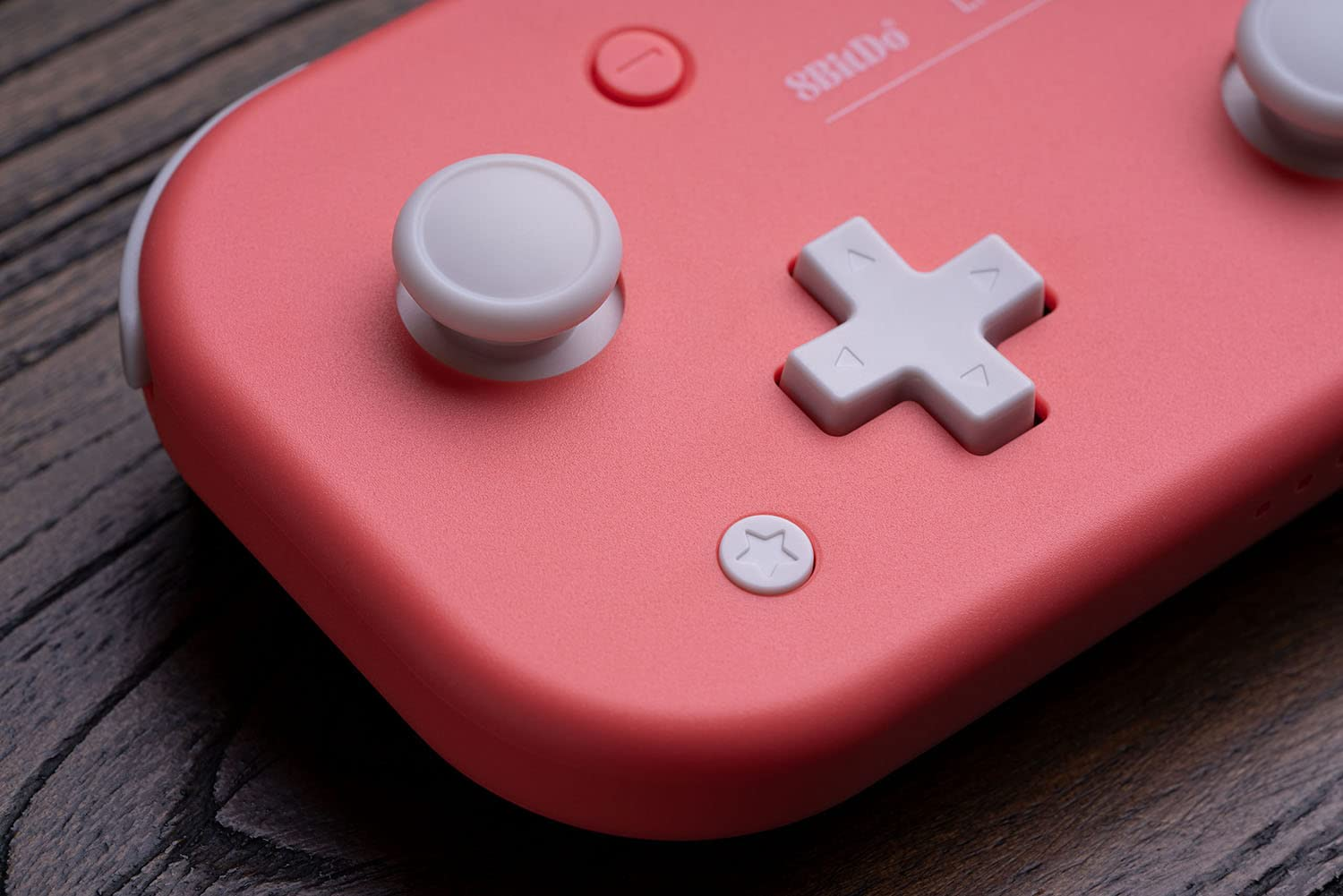 Primo piano di un controller rosa, con pulsanti bianchi e D-pad bianco, isolato su bianco.