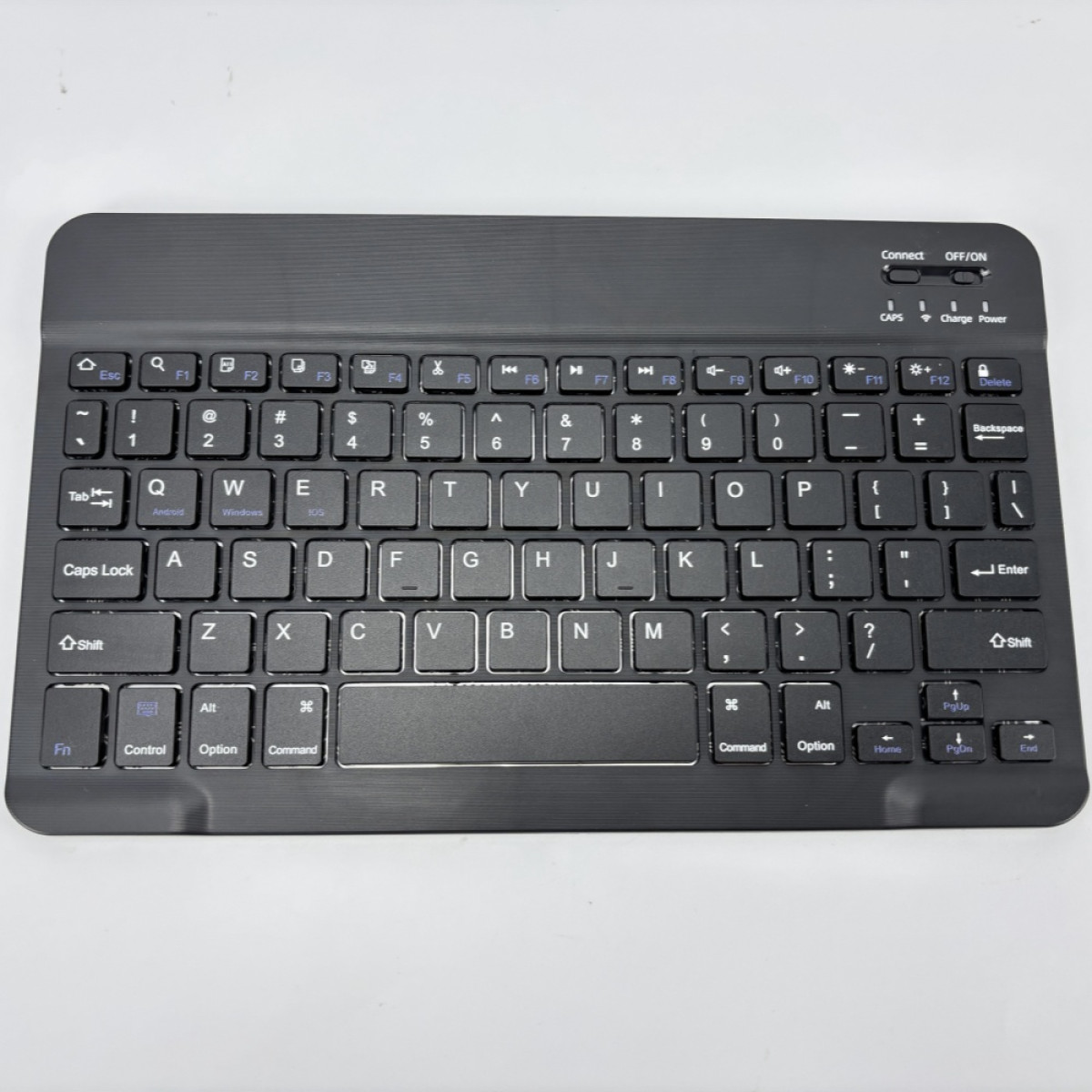 Eine schwarze kabellose Tastatur auf weißem Untergrund. Sie hat Tasten mit weißen Buchstaben und Zahlen. Die Tastatur hat ein Trackpad.