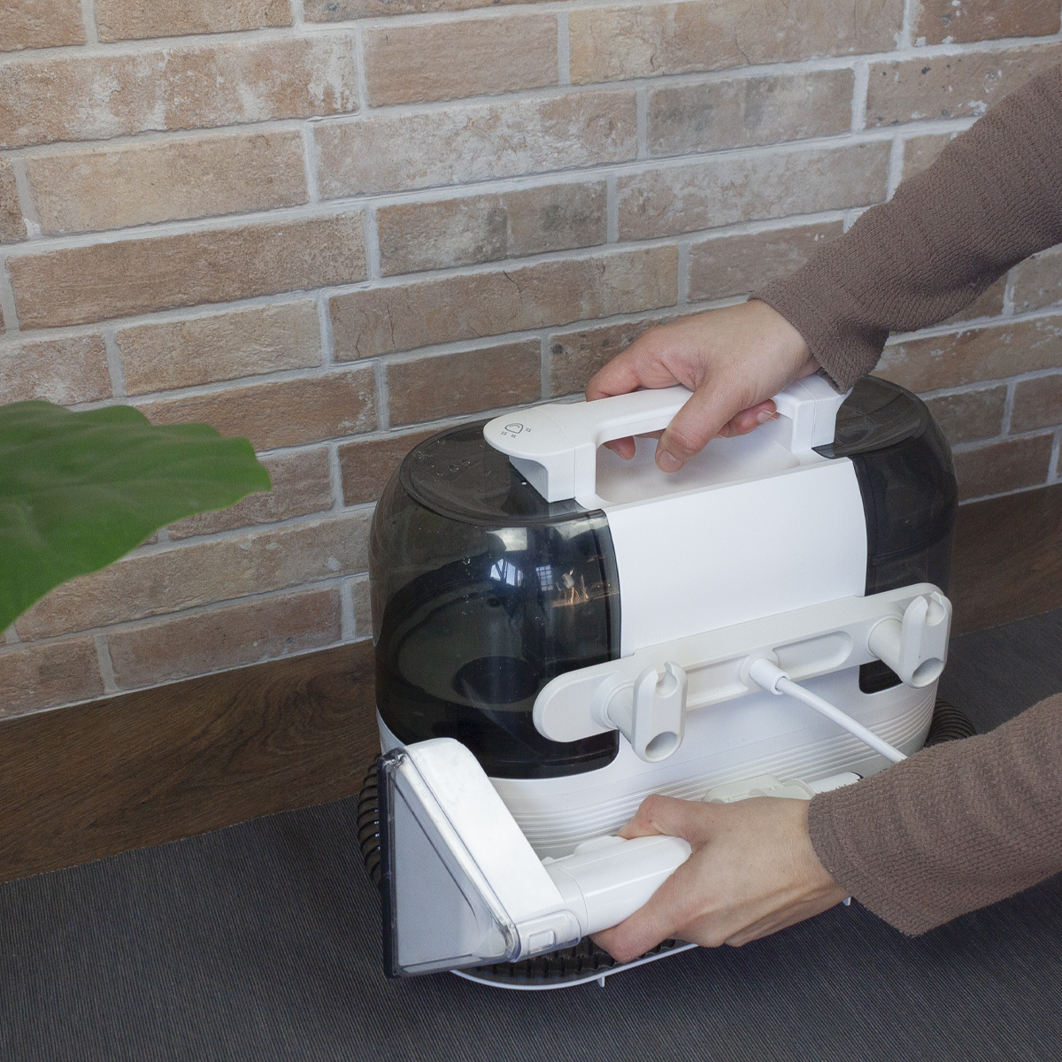 Osoba używająca białej maszyny czyszczącej na szarej powierzchni, blisko ściany.