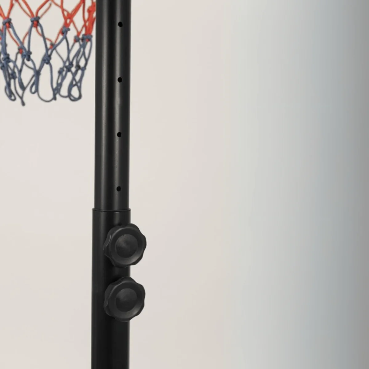 Close-up of the black pole of a basketball hoop. Knobs for adjusting the height.