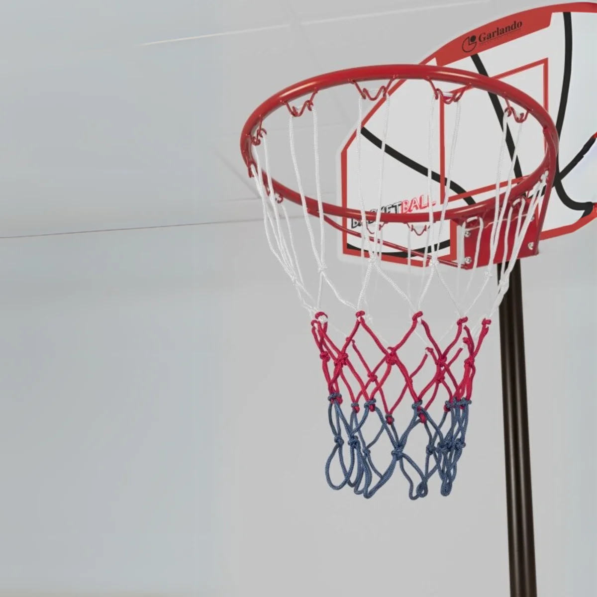 Close-up of a basketball hoop and net. The net is red, white, and blue.