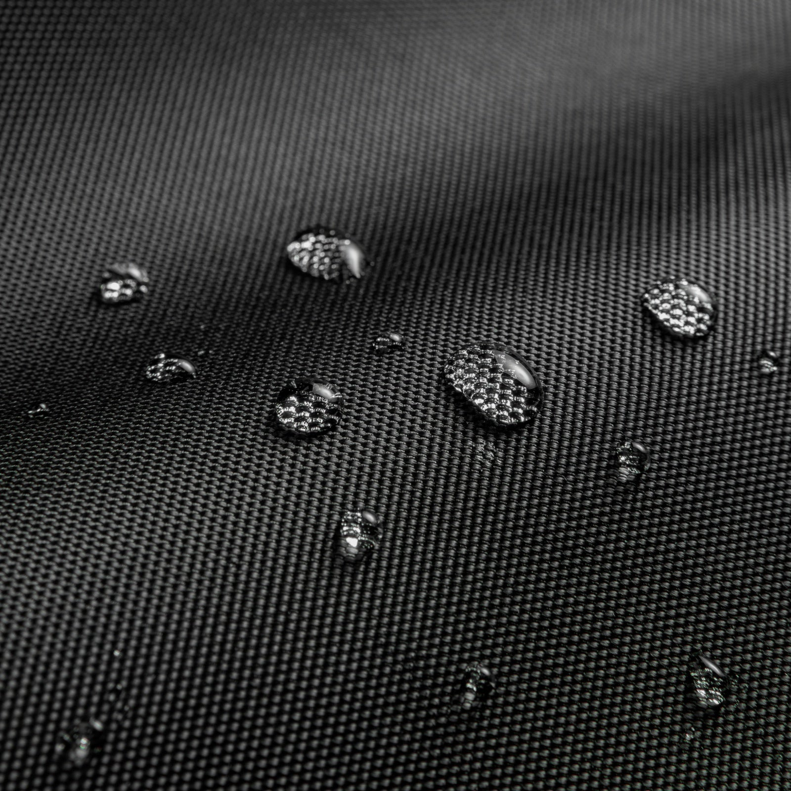 Zbliżenie kropelek wody na teksturowanej czarnej powierzchni, podkreślające wodoodporność.