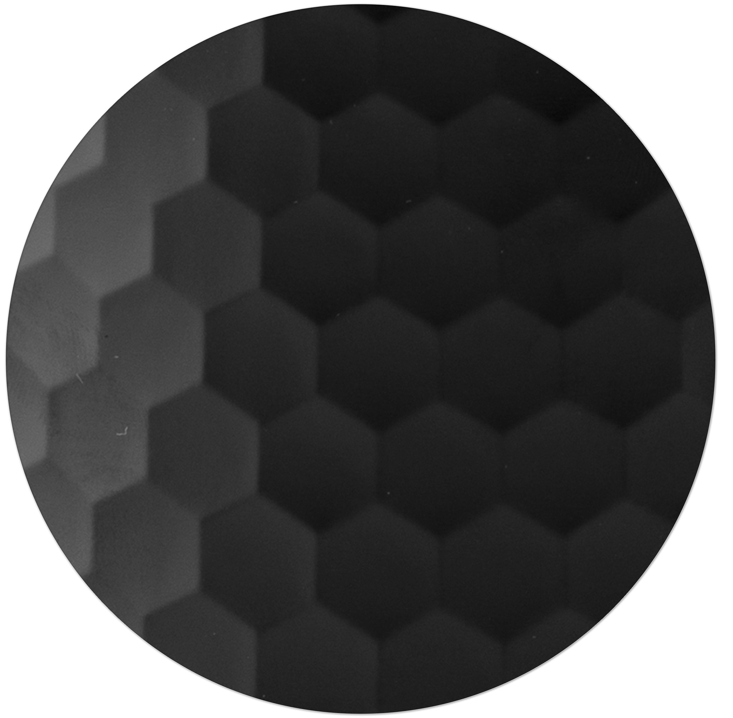 Zbliżenie czarnej powierzchni o wzorze plastra miodu. Sześciokąty są zacienione, tworząc efekt tekstury.