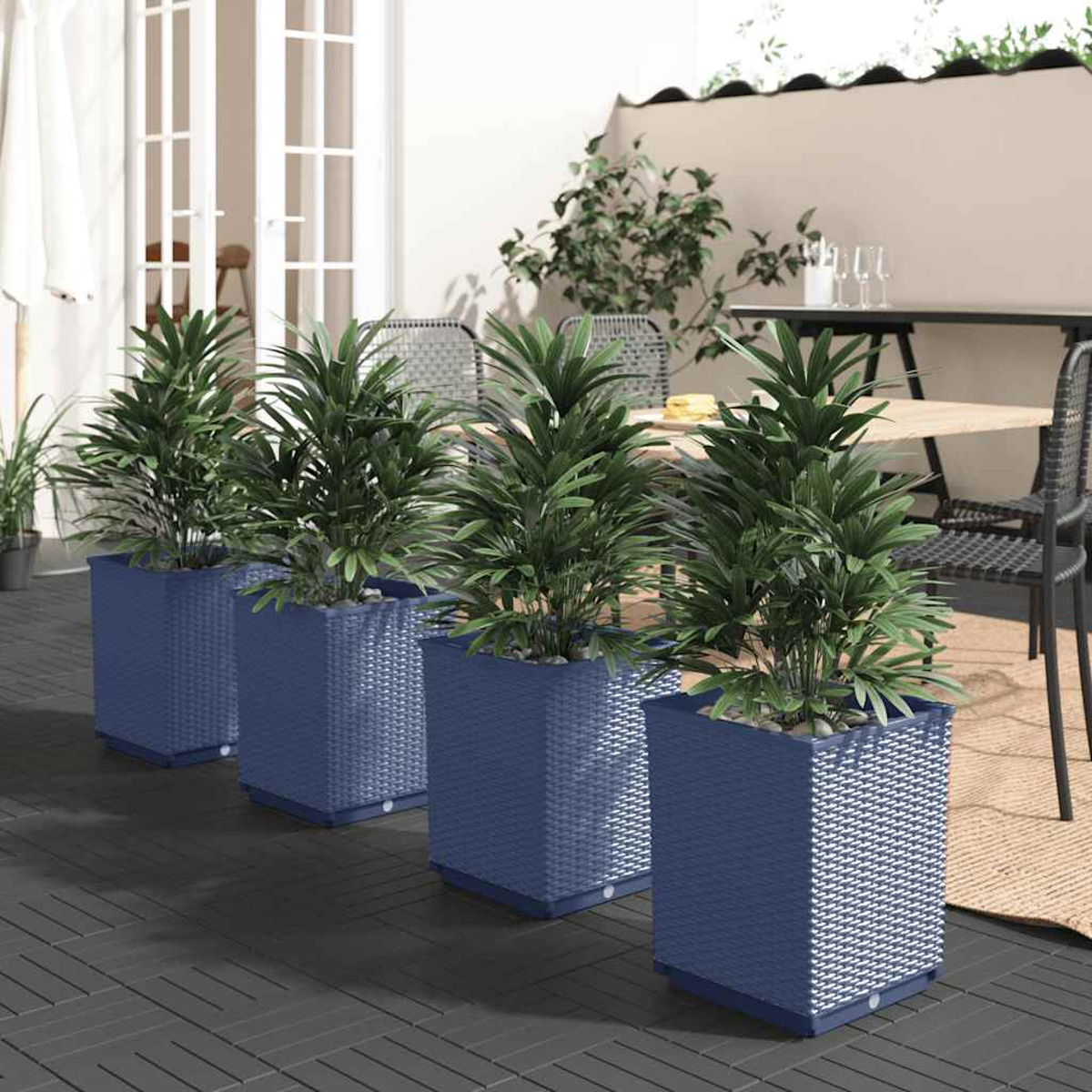 Vier blaue Pflanzgefäße mit grünen Pflanzen auf einer Terrasse. Eine Terrasse mit Tisch und Stühlen.