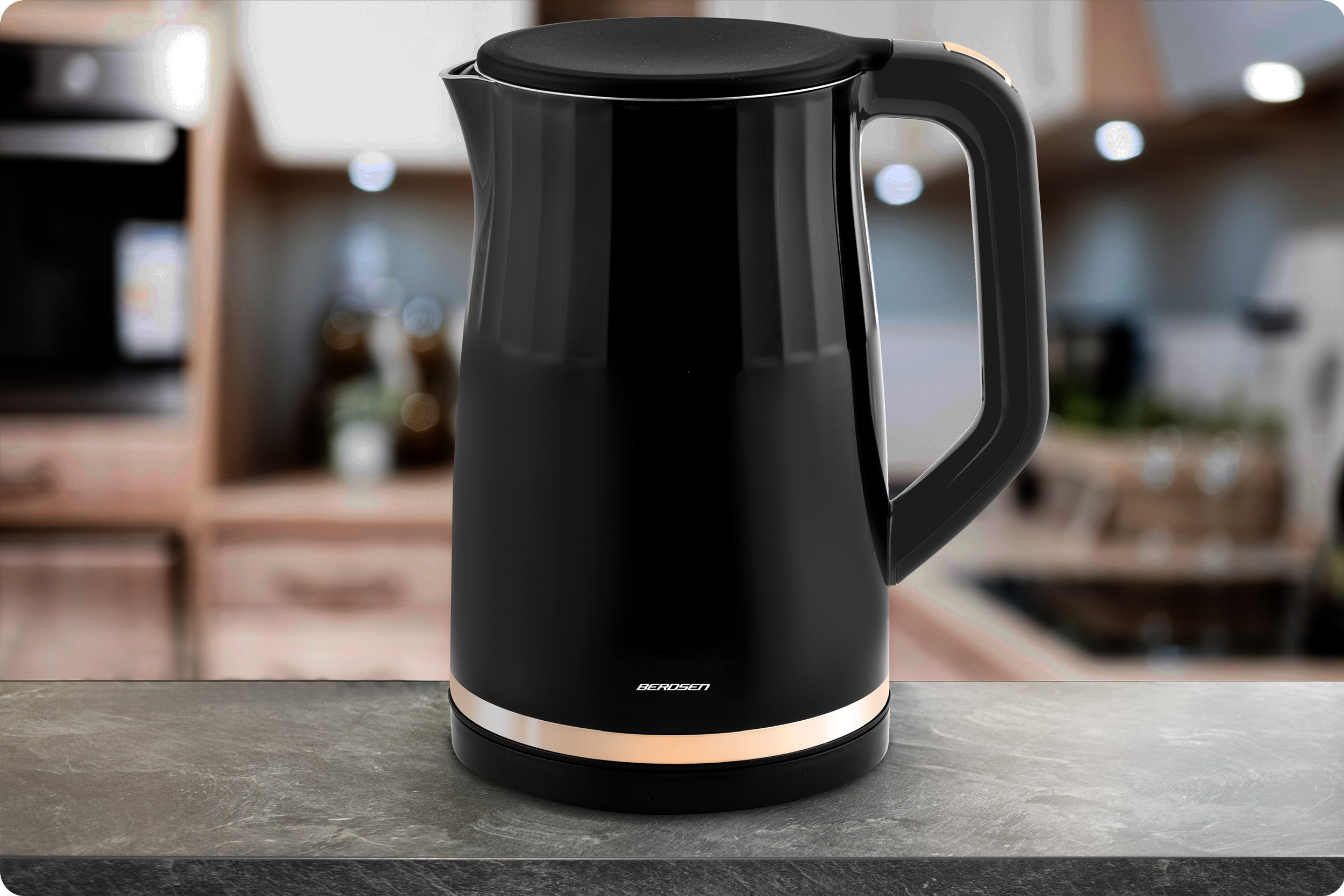 Czarny czajnik elektryczny na blacie. Tło kuchenne ze złotym wykończeniem wokół podstawy czajnika.