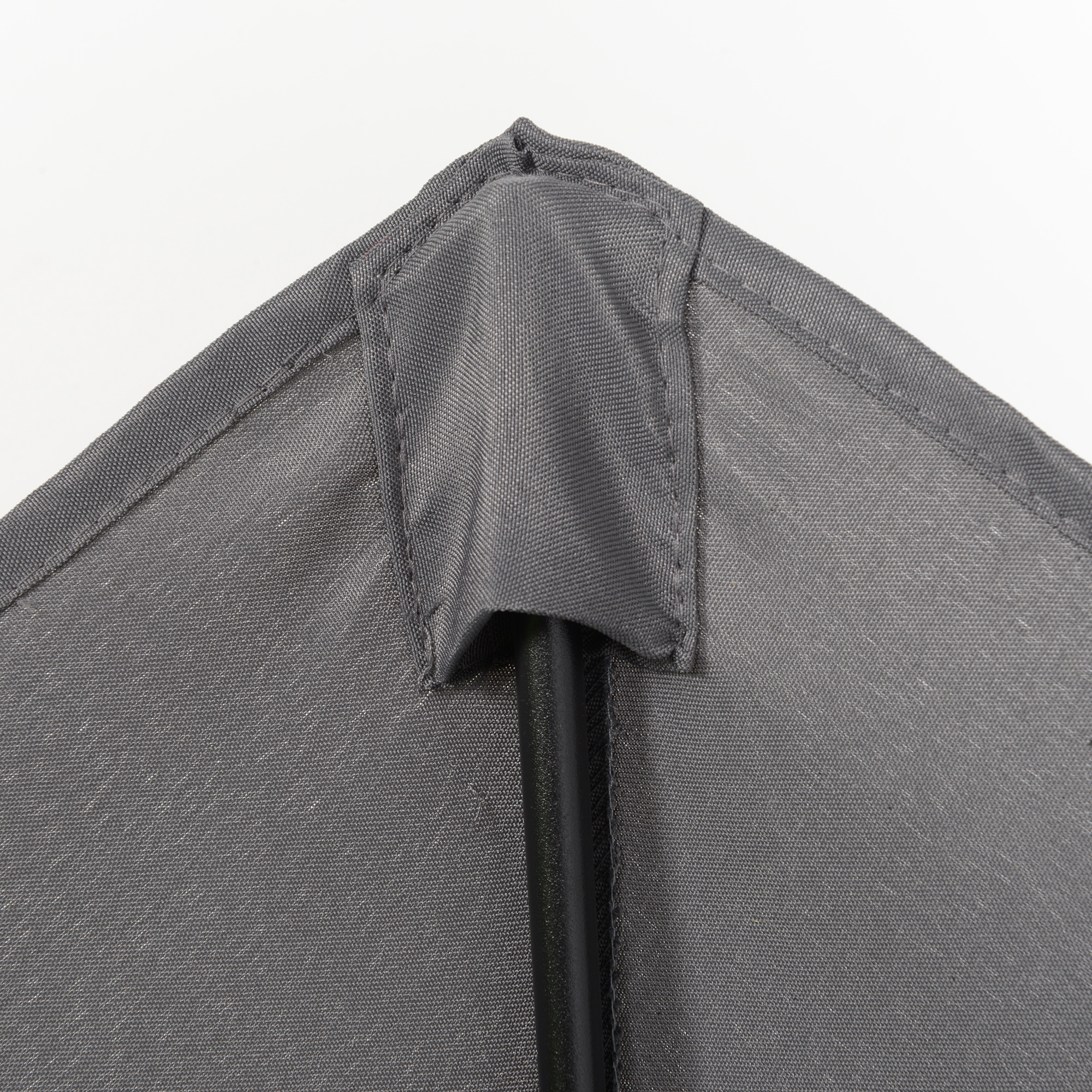 Graue Stoffecke mit Nähten, schwarze Stütze. Weißer Hintergrund.
