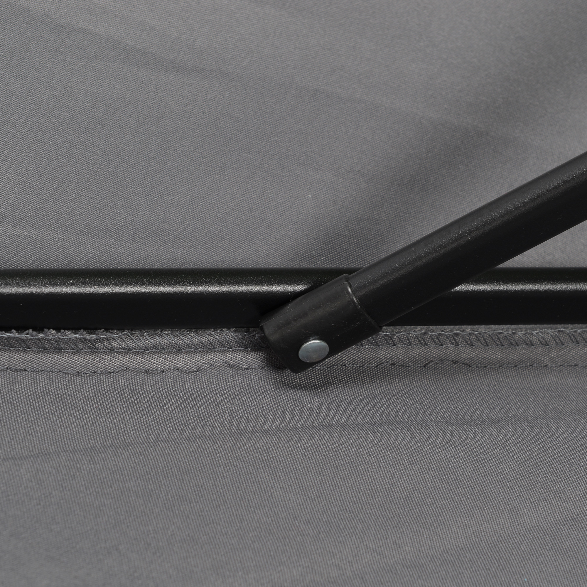 Nahaufnahme des grauen Schirmstoffs und Details des schwarzen Metallrahmens.
