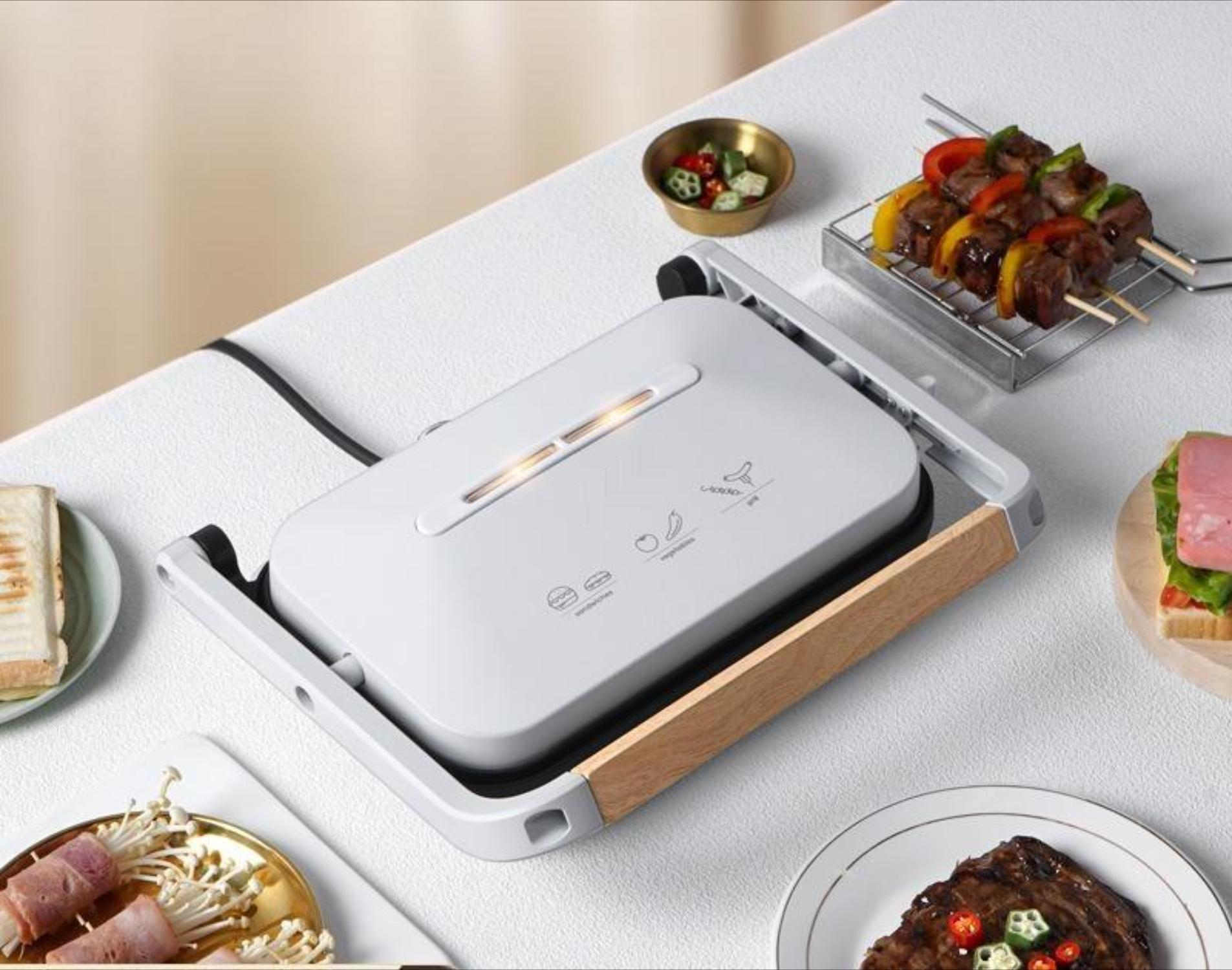 Geschlossene Panini-Presse mit Maßen und Essen. Weißer Hintergrund.