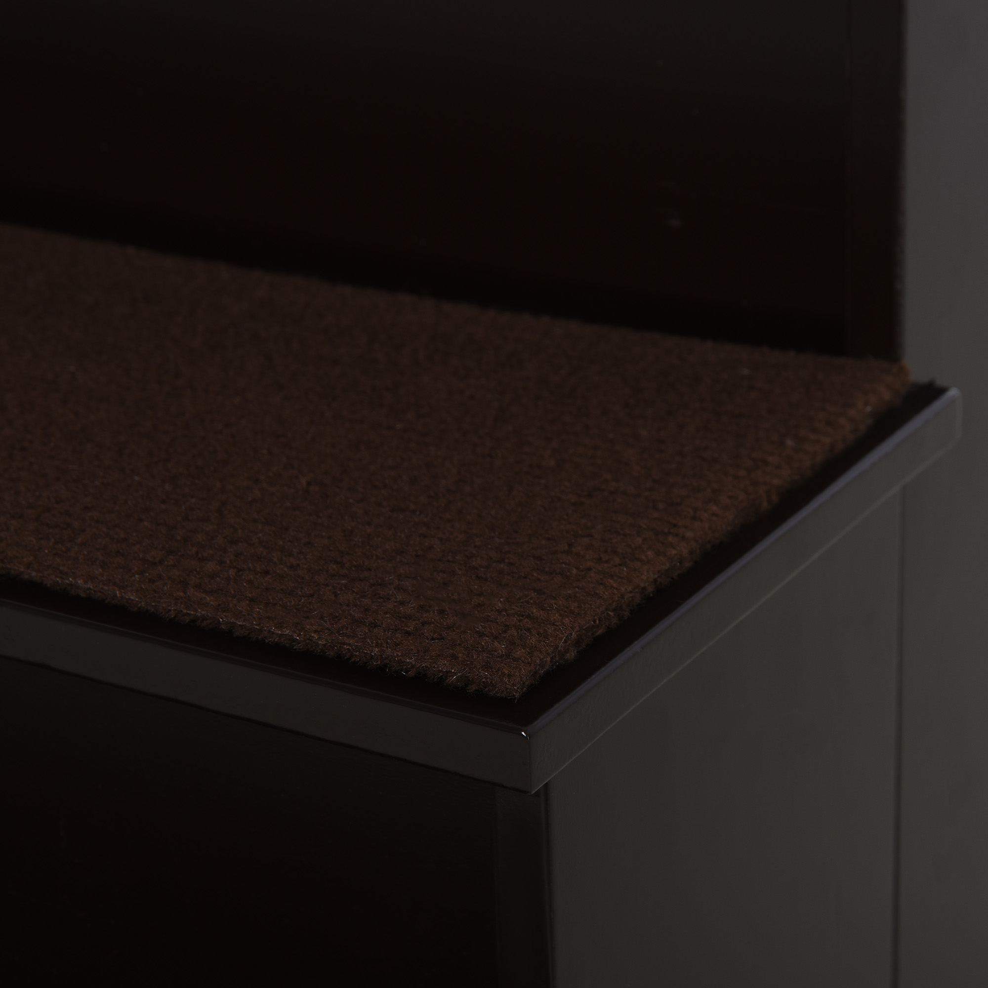 Nahaufnahme der Ecke einer braunen Haustiertreppe mit braunem Teppich.