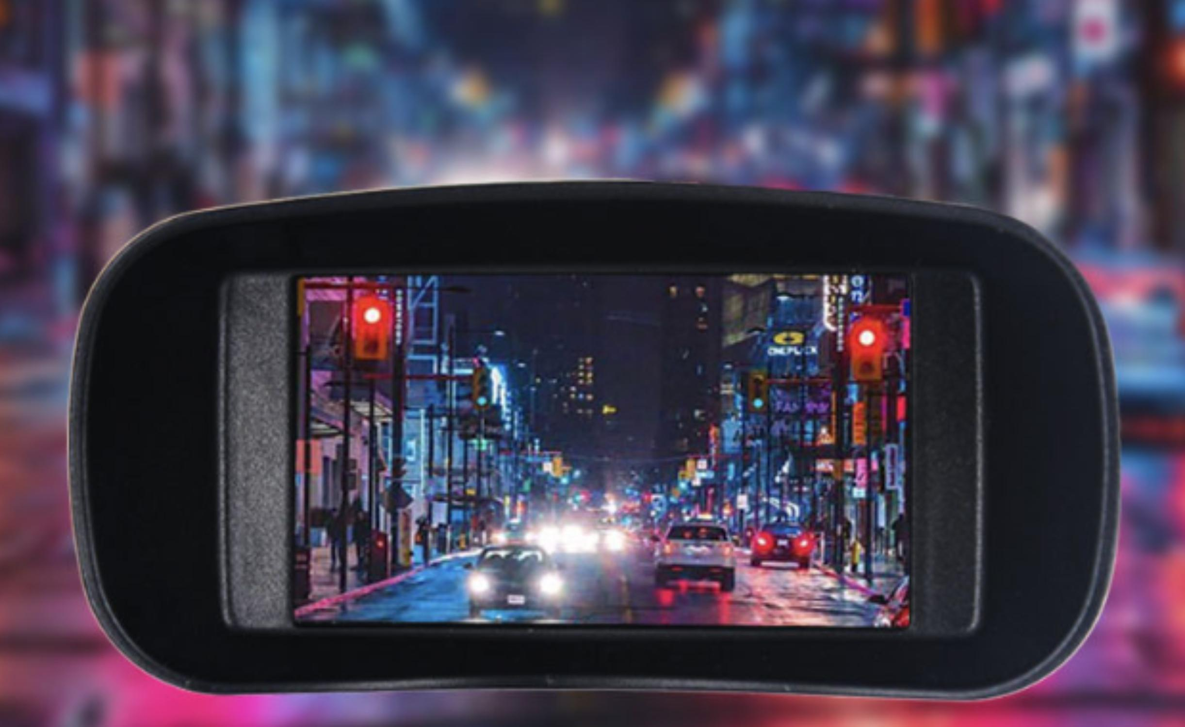 Ein schwarzes rechteckiges Display zeigt eine Stadtstraße mit Autos und Ampeln bei Nacht.