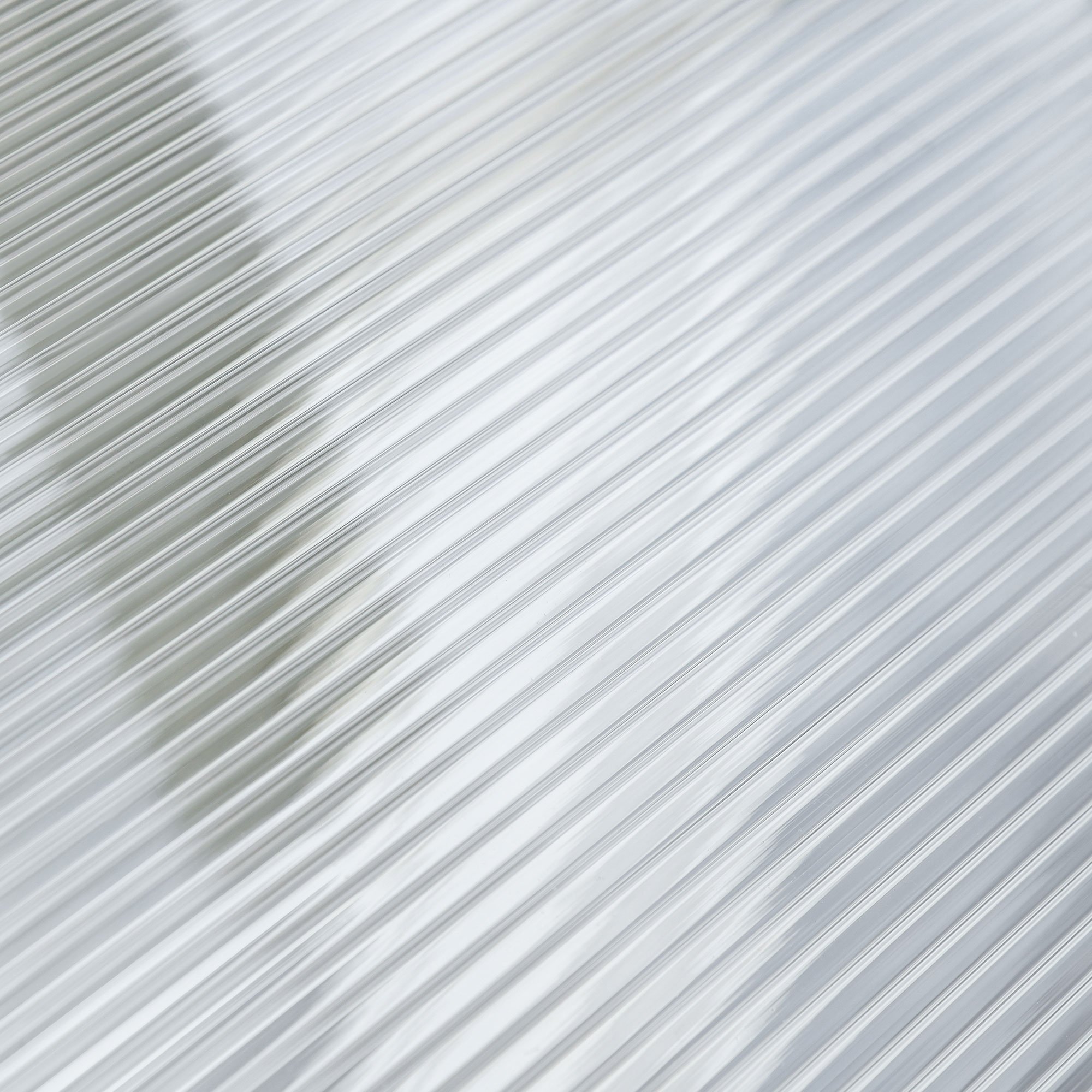 Eine Nahaufnahme von klarem, geriffeltem Kunststoffmaterial. Die Rippen verlaufen diagonal über die Ansicht.