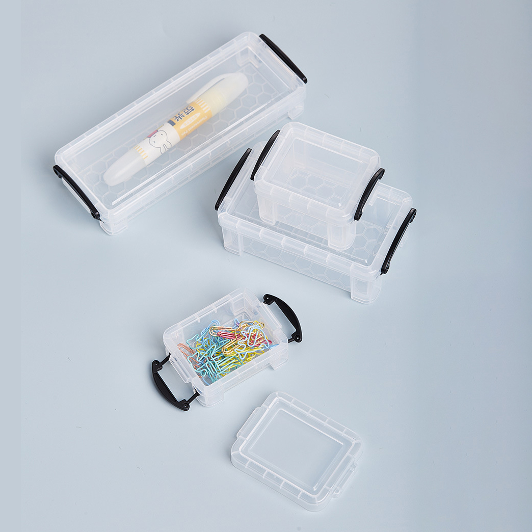 Transparente Plastikboxen verschiedener Größen, einige mit schwarzen Griffen, auf grauer Oberfläche angeordnet.