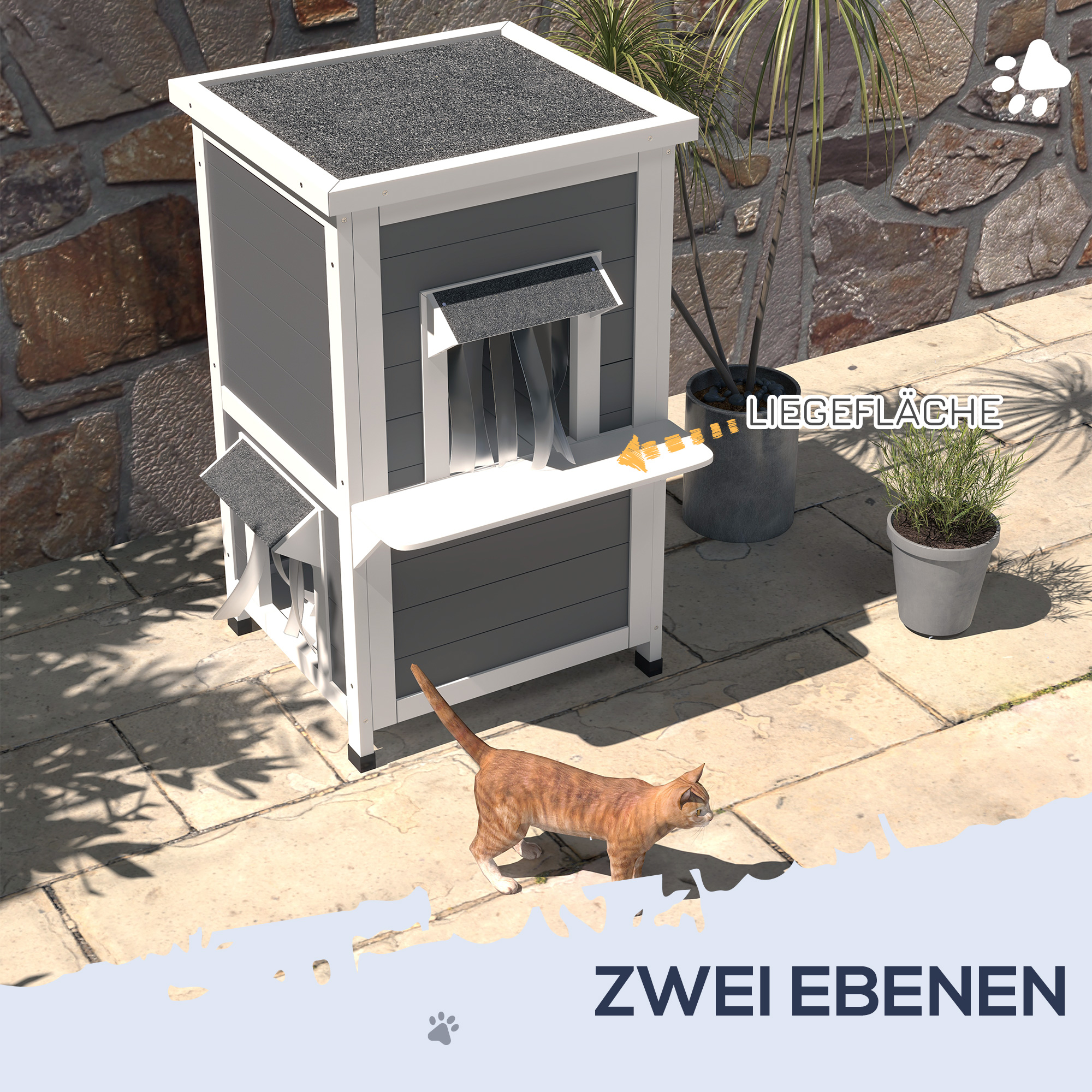 Ein grau-weißes Katzenhaus, vor dem eine Katze läuft. Steinmauer und Pflanzen im Hintergrund.