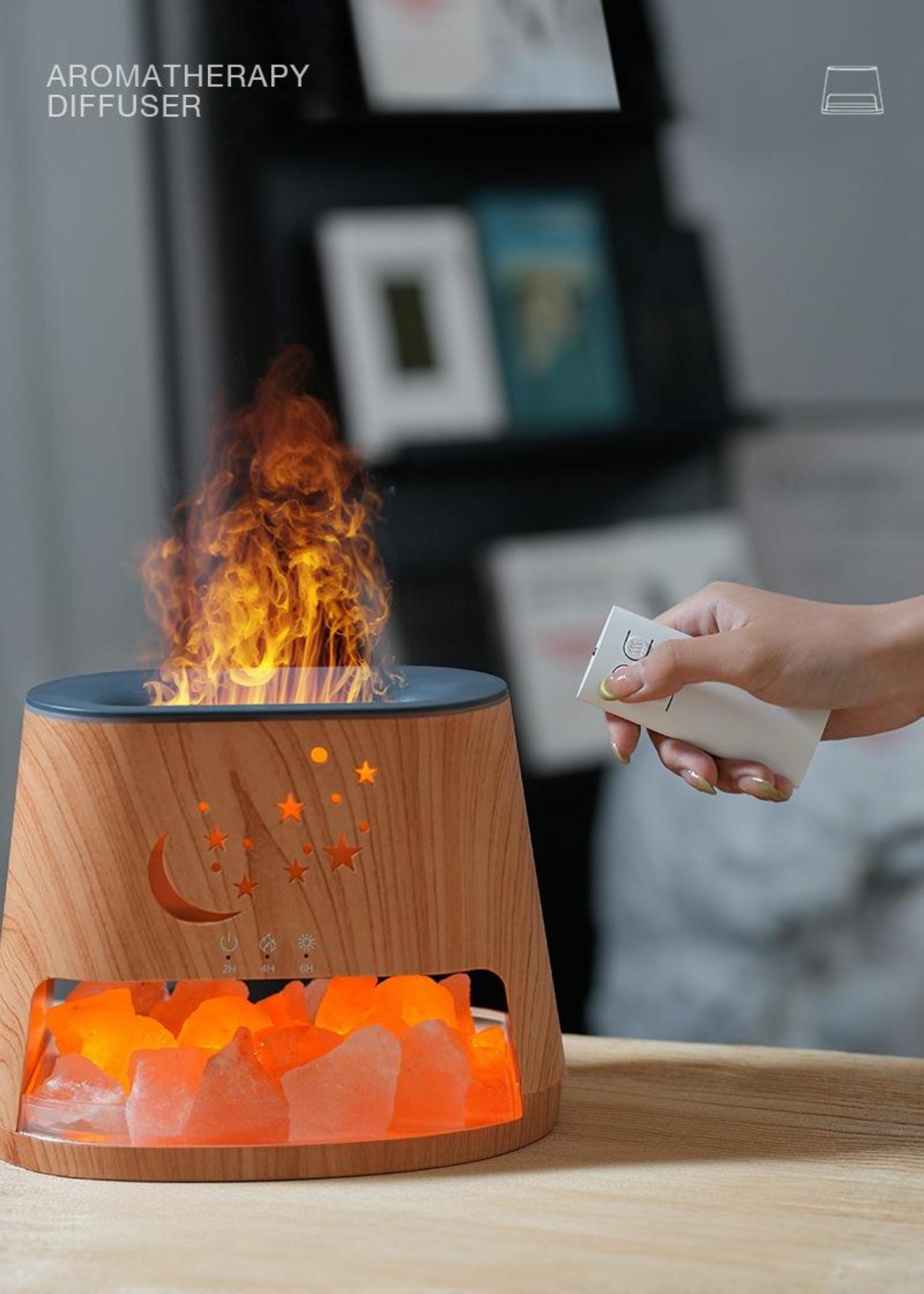 Holz-Aromadiffusor mit Flammen und Mond- und Sterne-Ausschnitt. Eine Hand hält eine Fernbedienung.