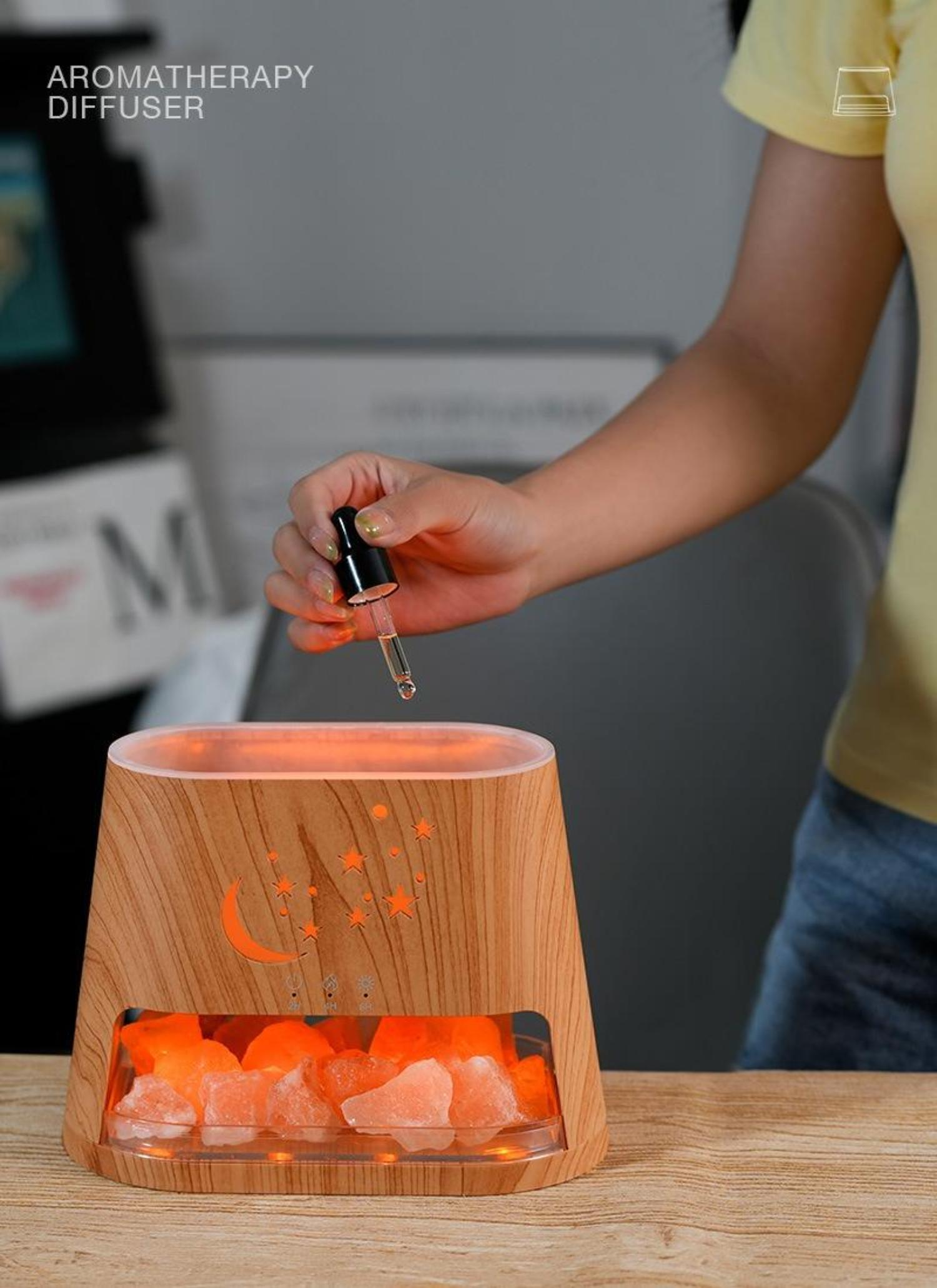 Eine Frau, die Tropfen aus einer Pipette in einen Aromatherapie-Diffusor mit Salzsteinen gibt.