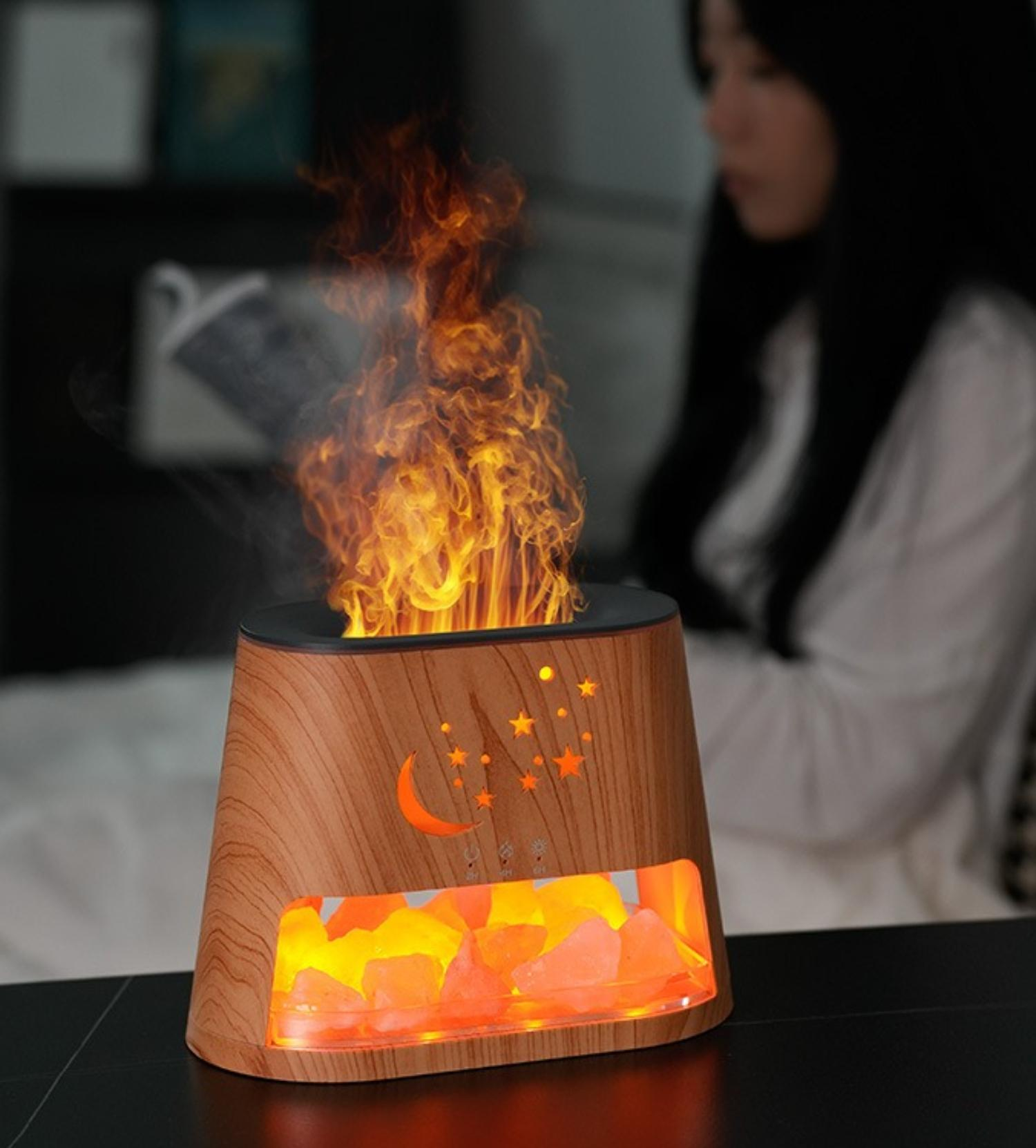 Ein Aromatherapie-Diffusor mit Flammeneffekt, Mond, Sternen und Salzsteinen mit einer Frau im Hintergrund.