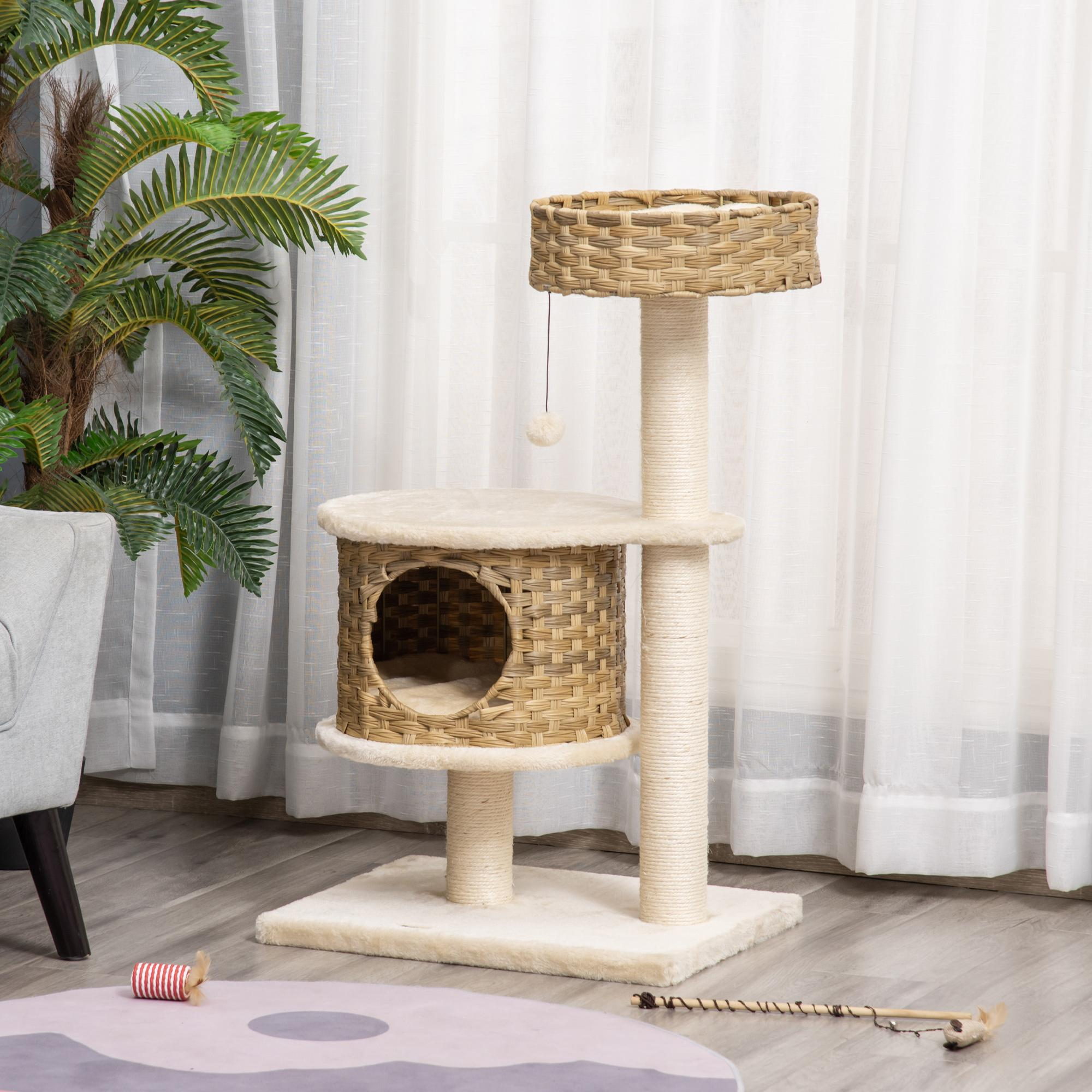 Kratzbaum mit Katzenhaus, beige und braun. Der Kratzbaum steht neben einem Fenster mit weißen Vorhängen.