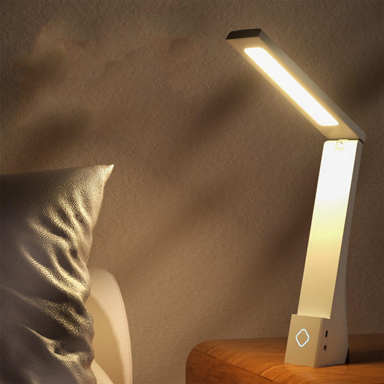 Eine weiße Schreibtischlampe mit rechteckigem Licht auf einem Holztisch, neben einem Kissen an einer beigen Wand.