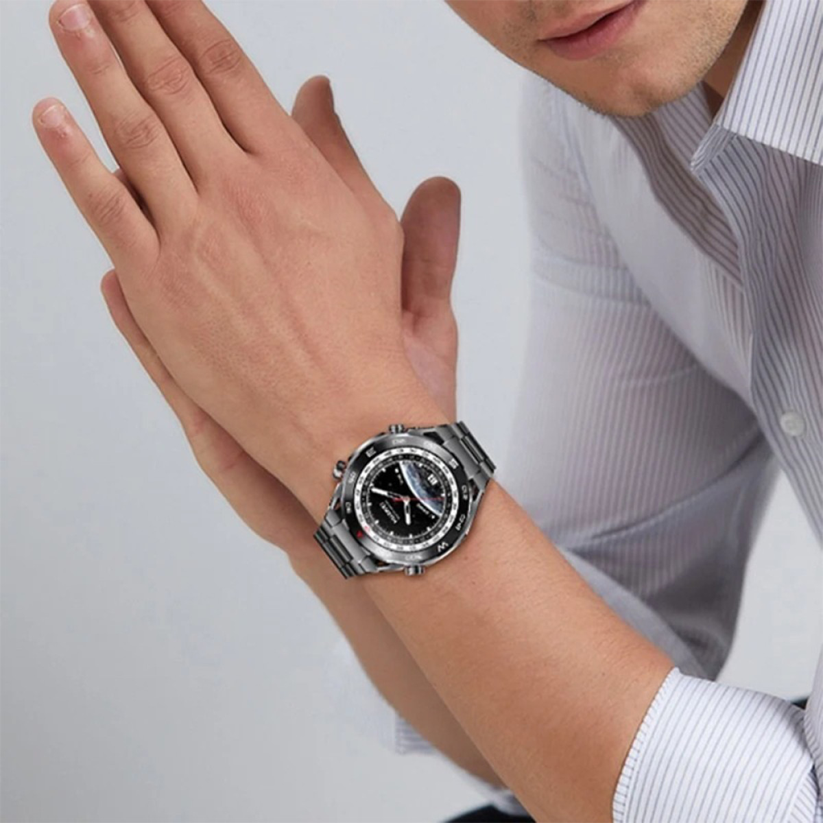 Ein Mann, der eine Uhr am Handgelenk trägt. Die Uhr hat ein schwarzes Zifferblatt und ein Metallarmband.