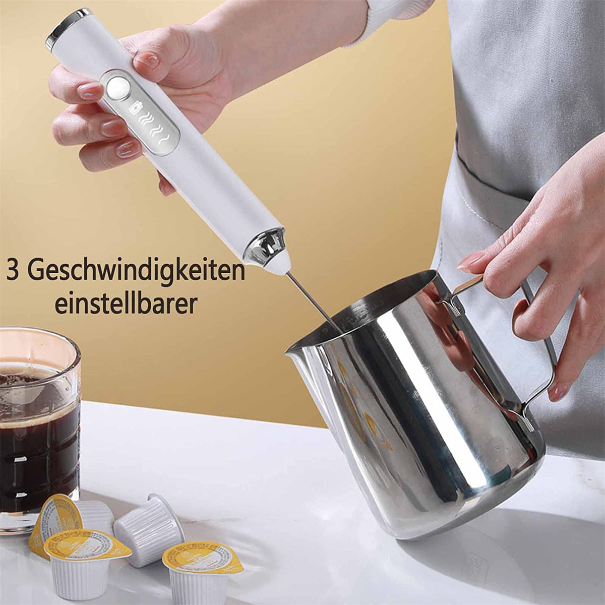 Eine Person verwendet einen weißen Milchaufschäumer, um Milch in einen Edelstahlkrug aufzuschäumen.