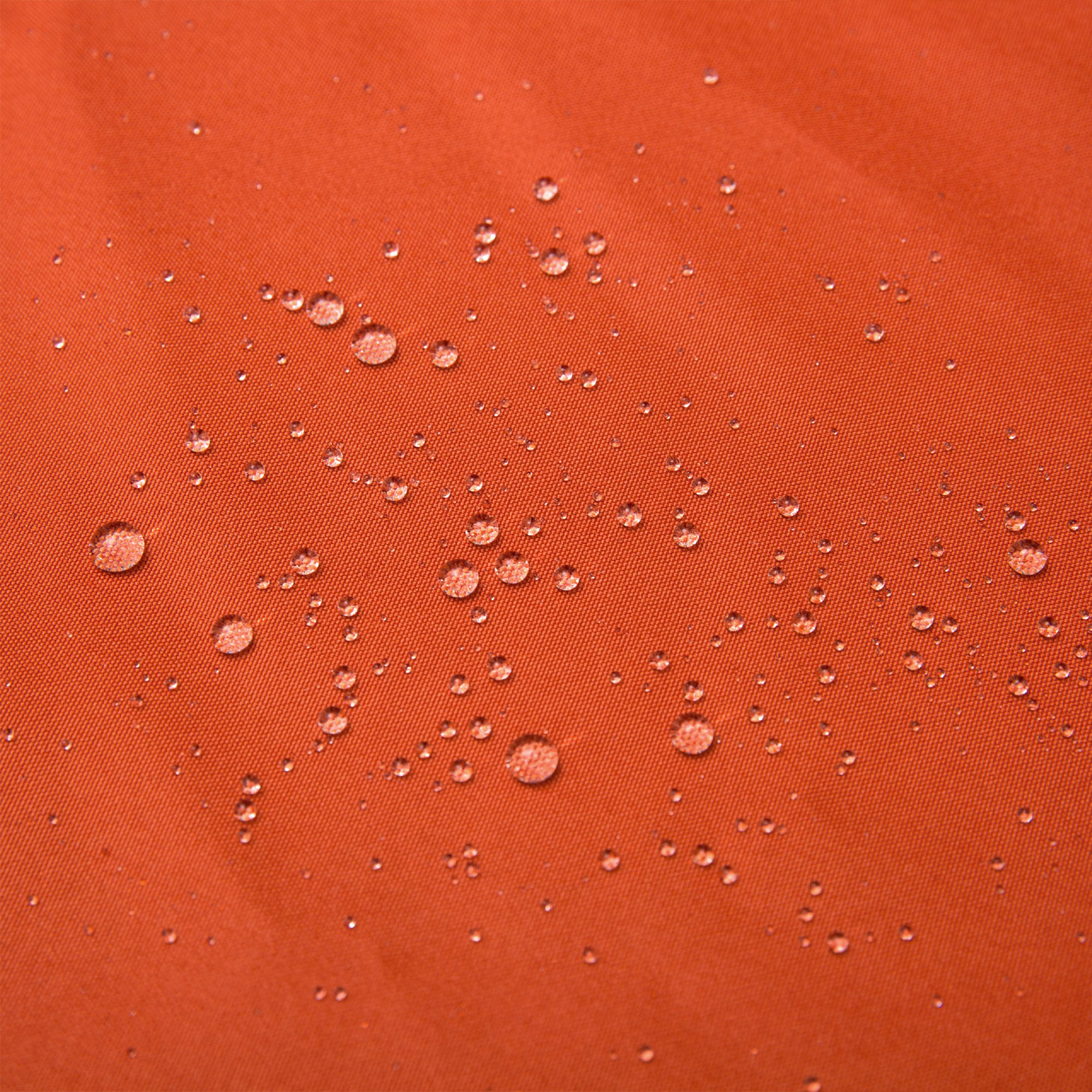 Nahaufnahme eines orangefarbenen Stoffes mit Wassertropfen auf der Oberfläche. Der Stoff hat ein leicht strukturiertes Aussehen.
