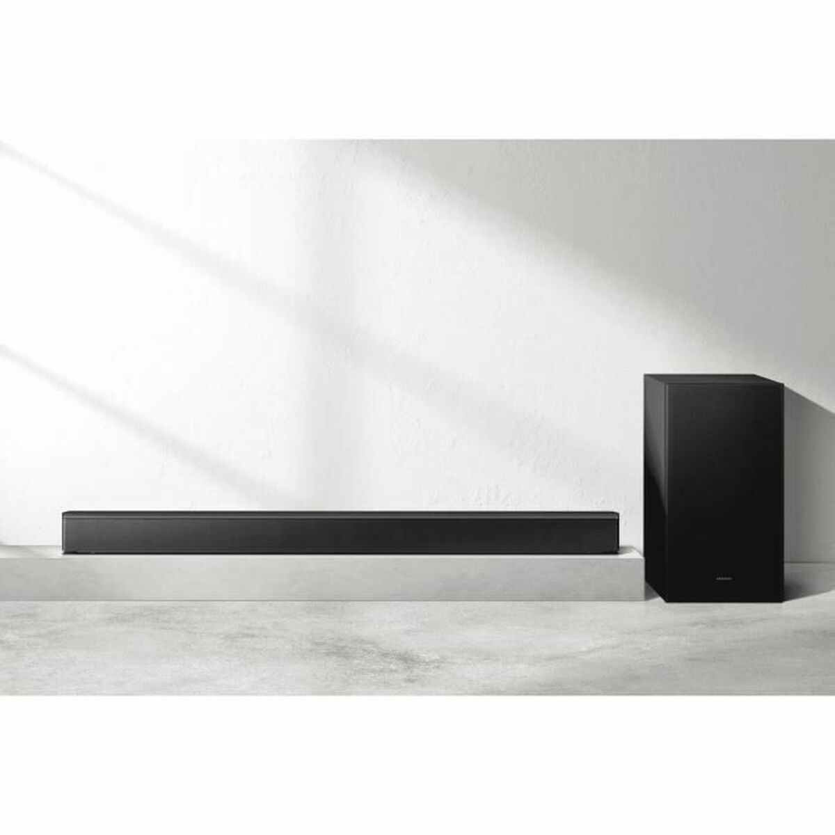 Una soundbar nera e un subwoofer nero su una superficie bianca. Sono su un supporto. Sfondo bianco.