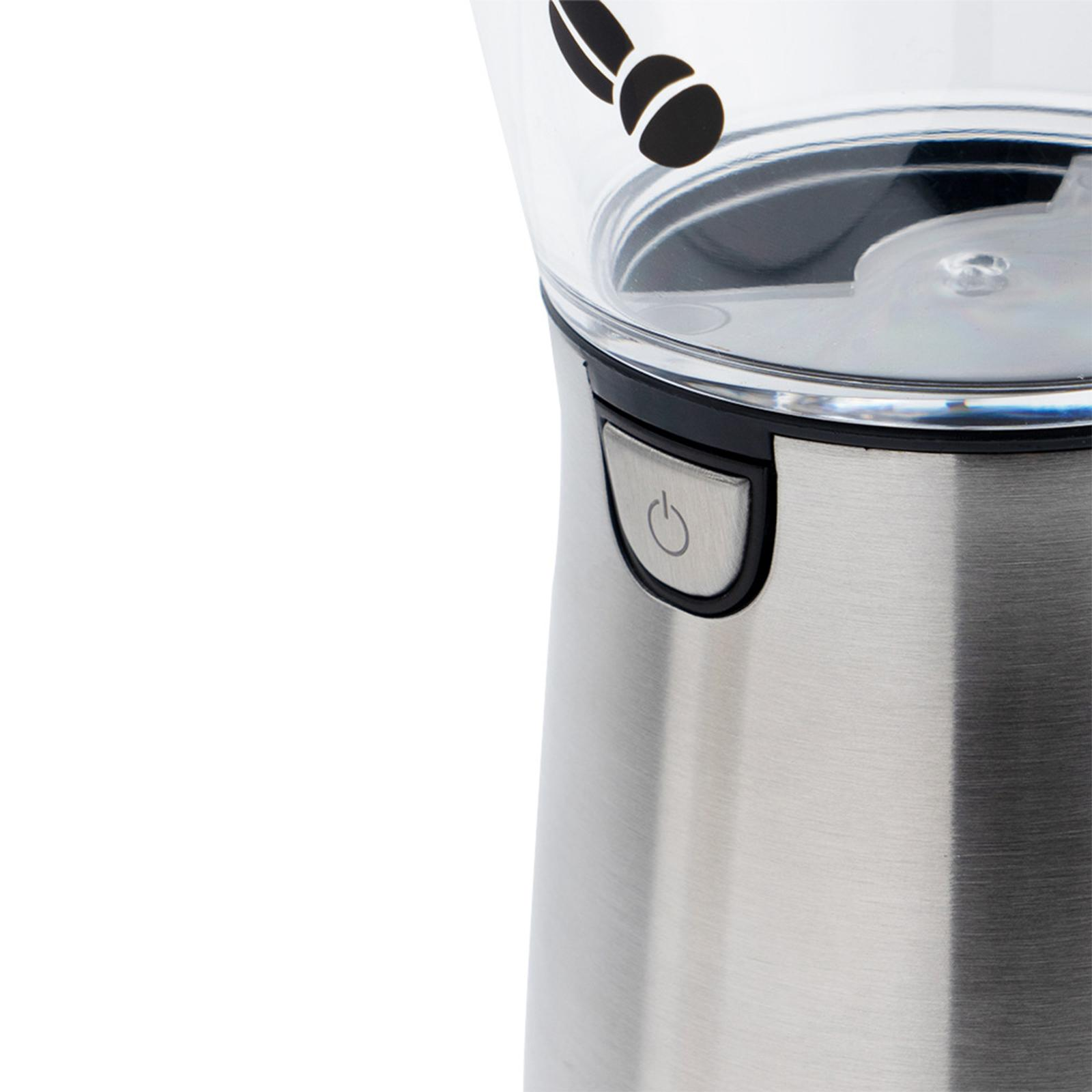 Nahaufnahme einer metallischen Kaffeemühle. Ein Einschaltknopf ist auf der Vorderseite sichtbar. Schwarze Bohnen auf dem Deckel.