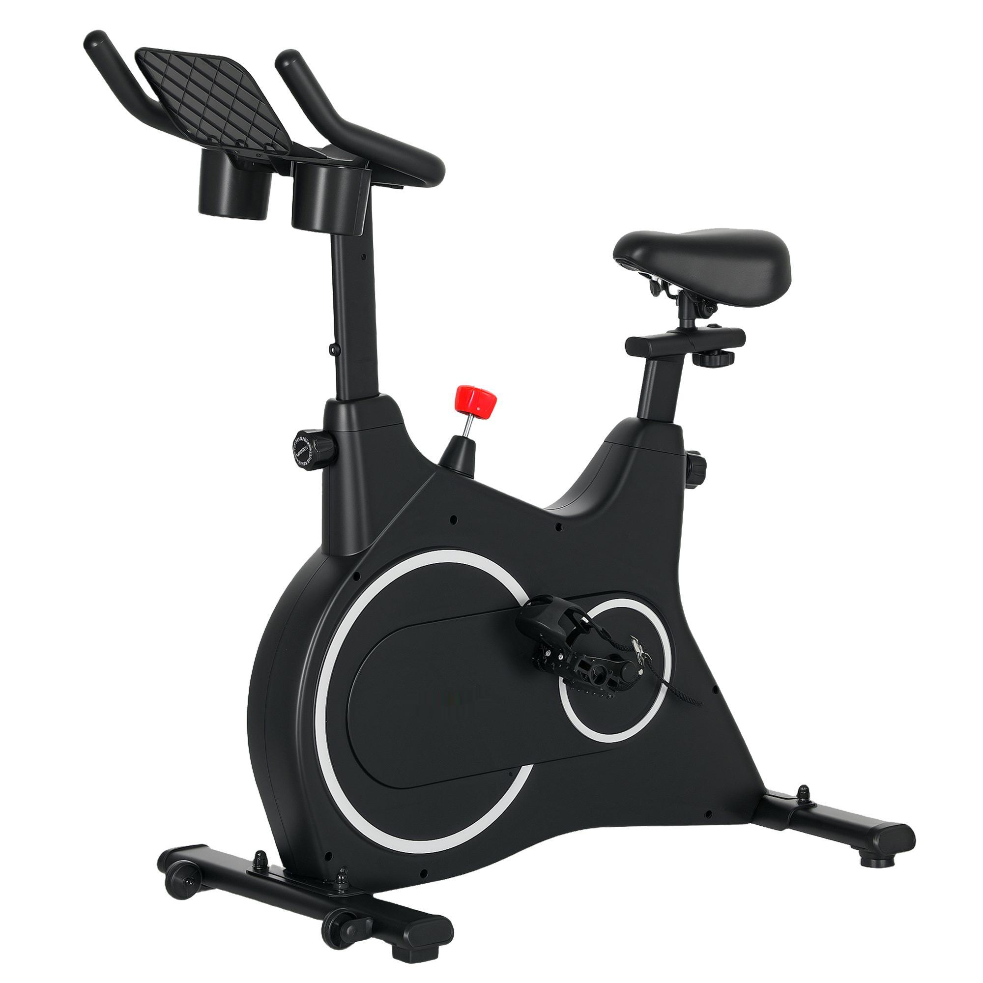 Ein schwarzes stationäres Fahrrad mit rotem Verstellknopf und weißem Ringdetail am Rad, schräge Aufnahme.