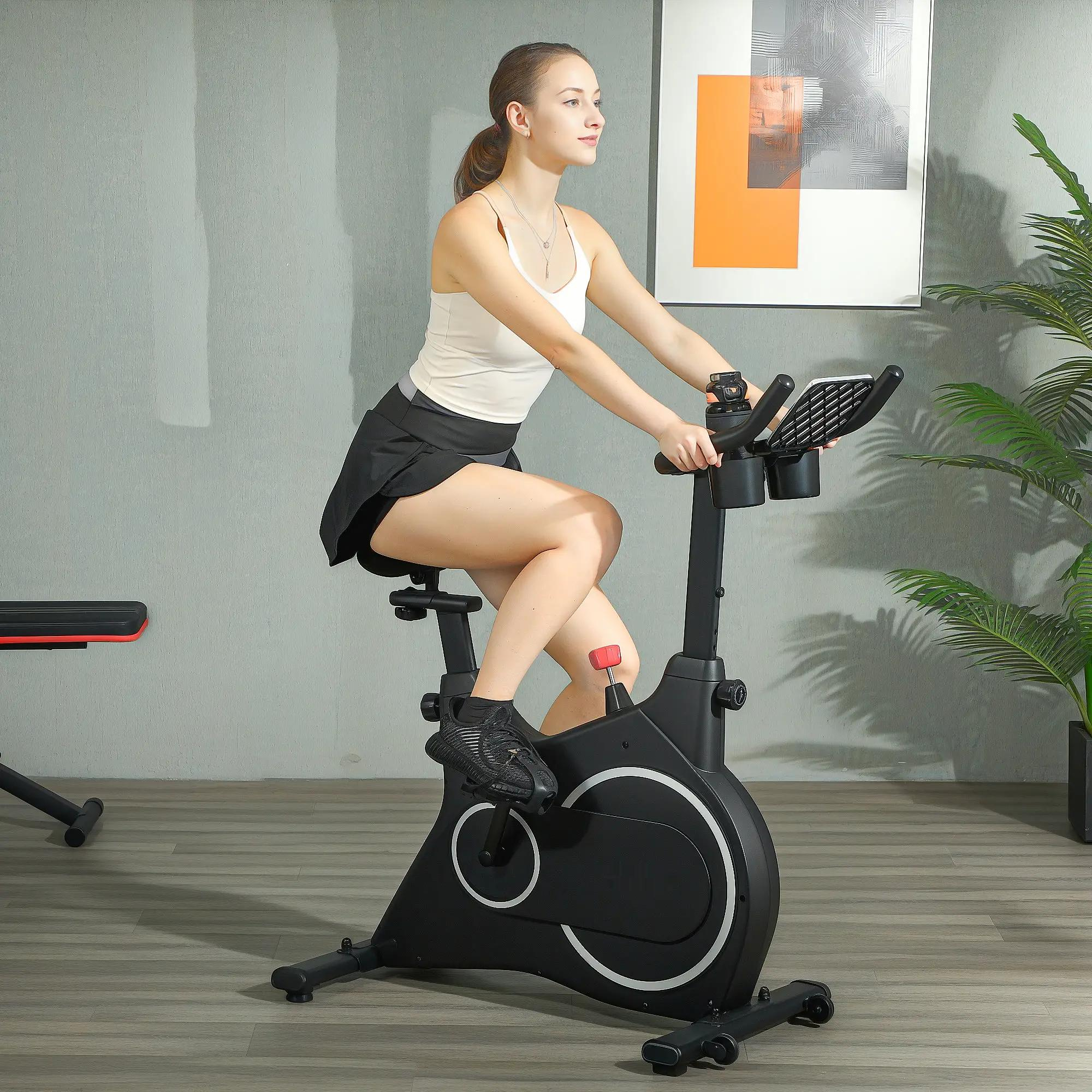 Eine Frau auf einem schwarzen Heimtrainer in einem Raum mit einem Gemälde und einer Pflanze.