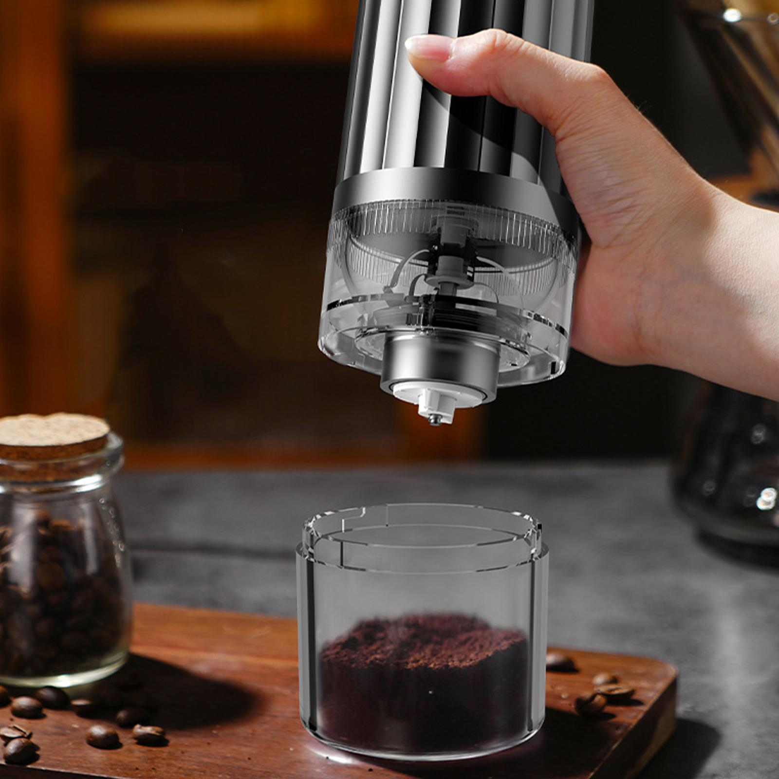 Eine Hand hält eine Mühle und gießt gemahlenen Kaffee in einen Behälter.