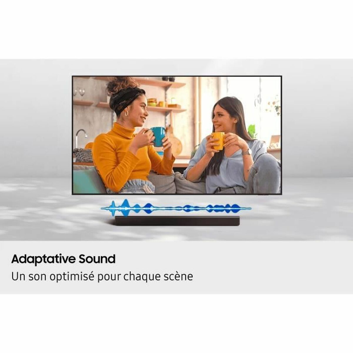 Zwei Frauen sitzen und lächeln vor einem Fernseher. Unter dem Bildschirm steht Text.