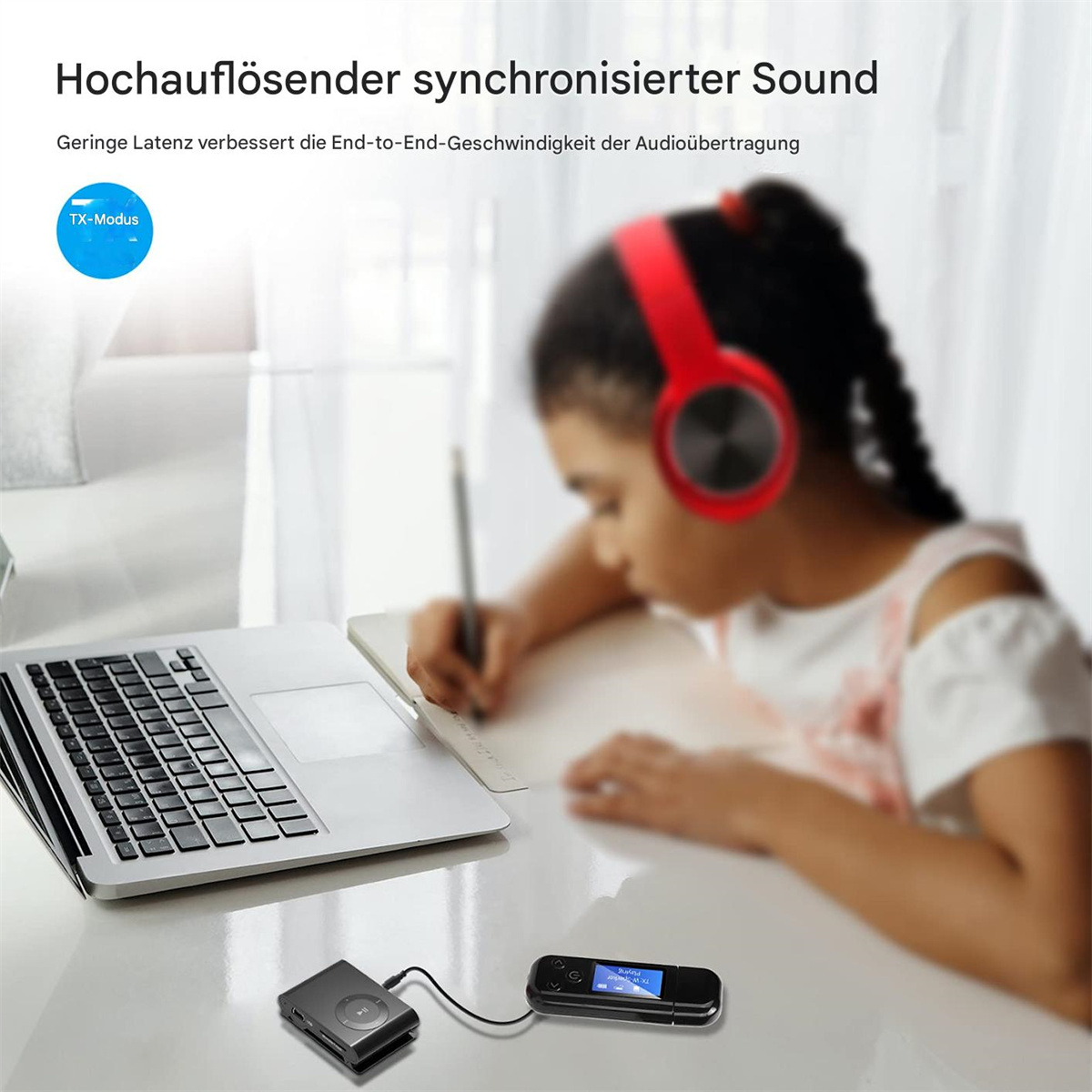 Ein Mädchen mit roten Kopfhörern schreibt in ein Notizbuch. Ein Laptop und ein schwarzes Gerät stehen auf dem Tisch.