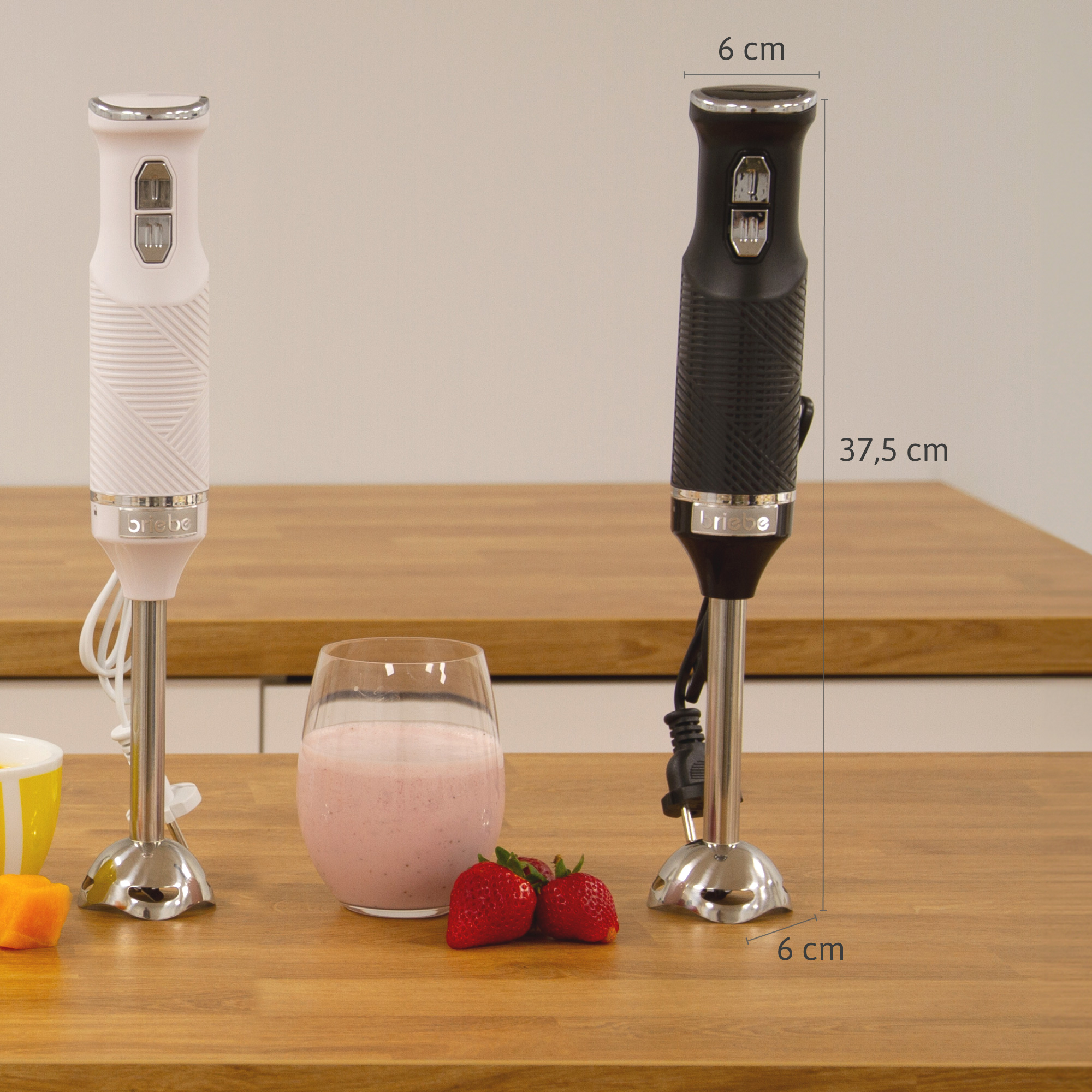 Dos batidoras de mano, una blanca y otra negra, con un batido y fresas sobre una mesa.