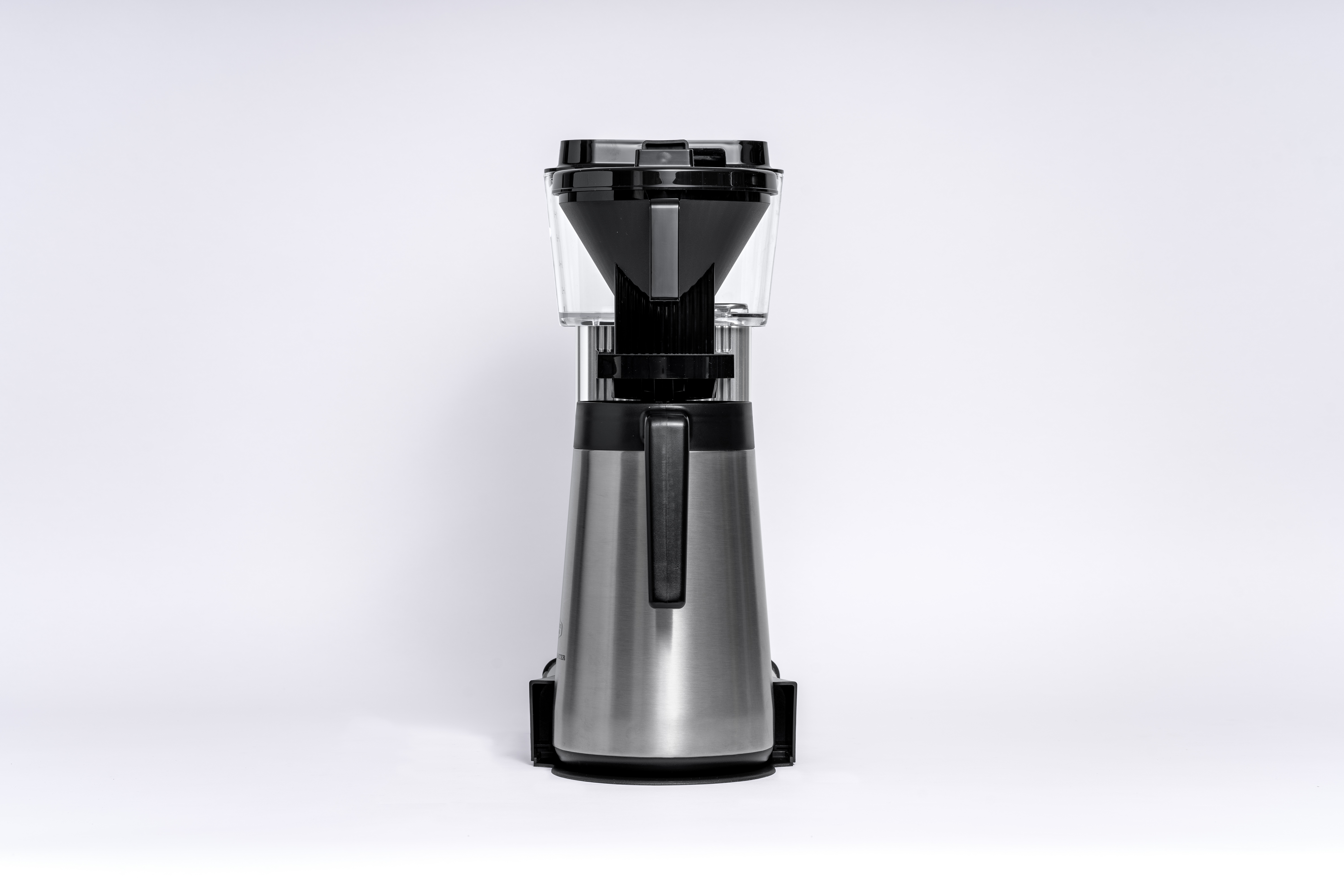 Une cafetière argentée et noire. Elle a un réservoir d'eau transparent et un filtre noir.
