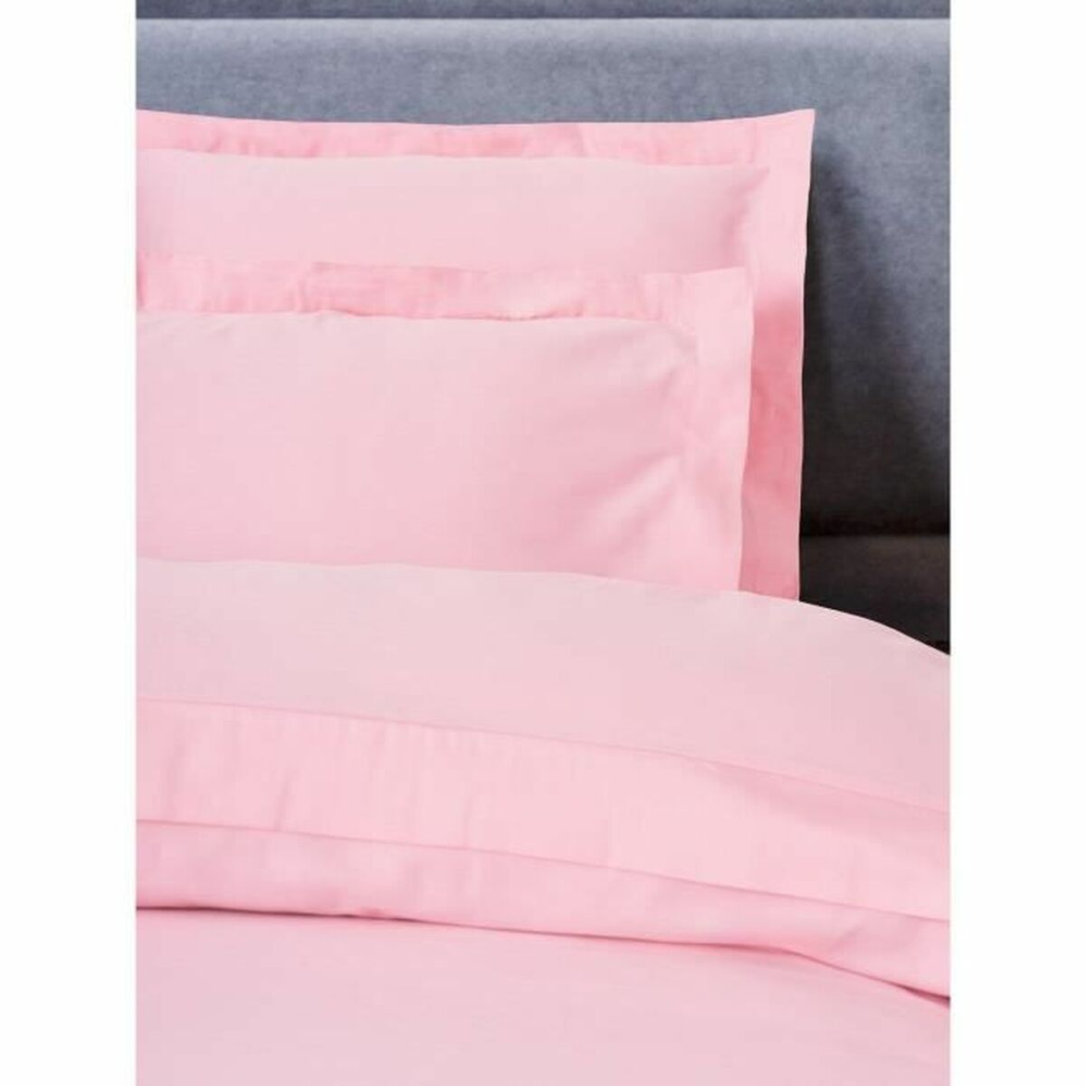 Rosa Bettwäsche-Set mit Kissen und Bettdecke auf grauem Hintergrund. Das Set ist sauber und schlicht, mit weichem Aussehen.