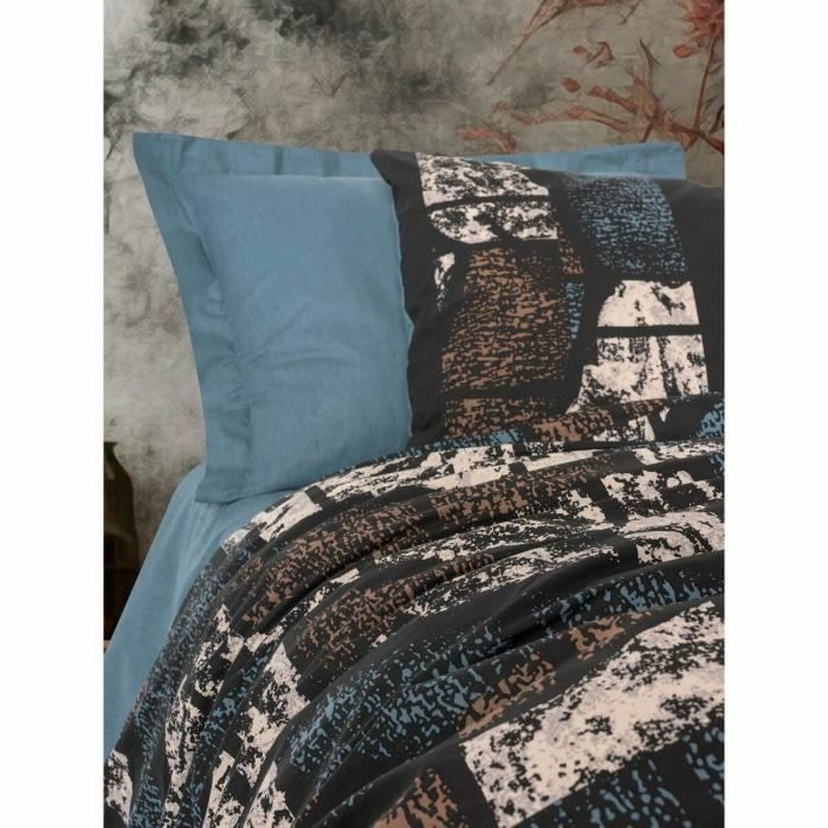 Nahaufnahme eines Bettes mit blauen Laken und gemusterten Kissen und Decken.