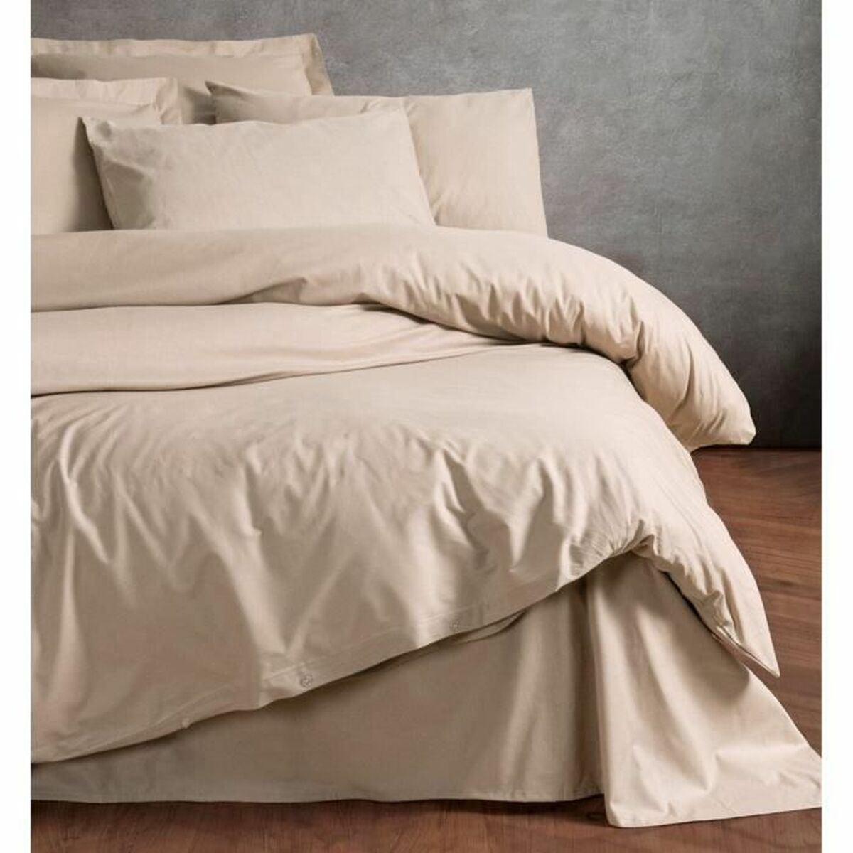 Ein Bett mit beiger Bettwäsche und Kissen.