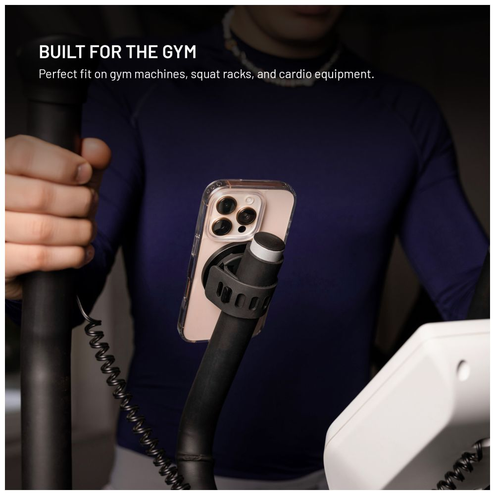 Ein Telefon ist an Fitnessgeräten montiert. Eine Person mit blauem Hemd ist im Hintergrund.