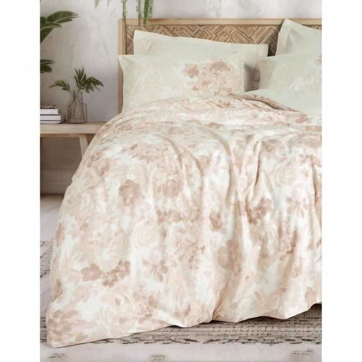 Ein Bett mit einer Bettdecke und Kissen mit floralem Muster. Die Farben sind weich und neutral.