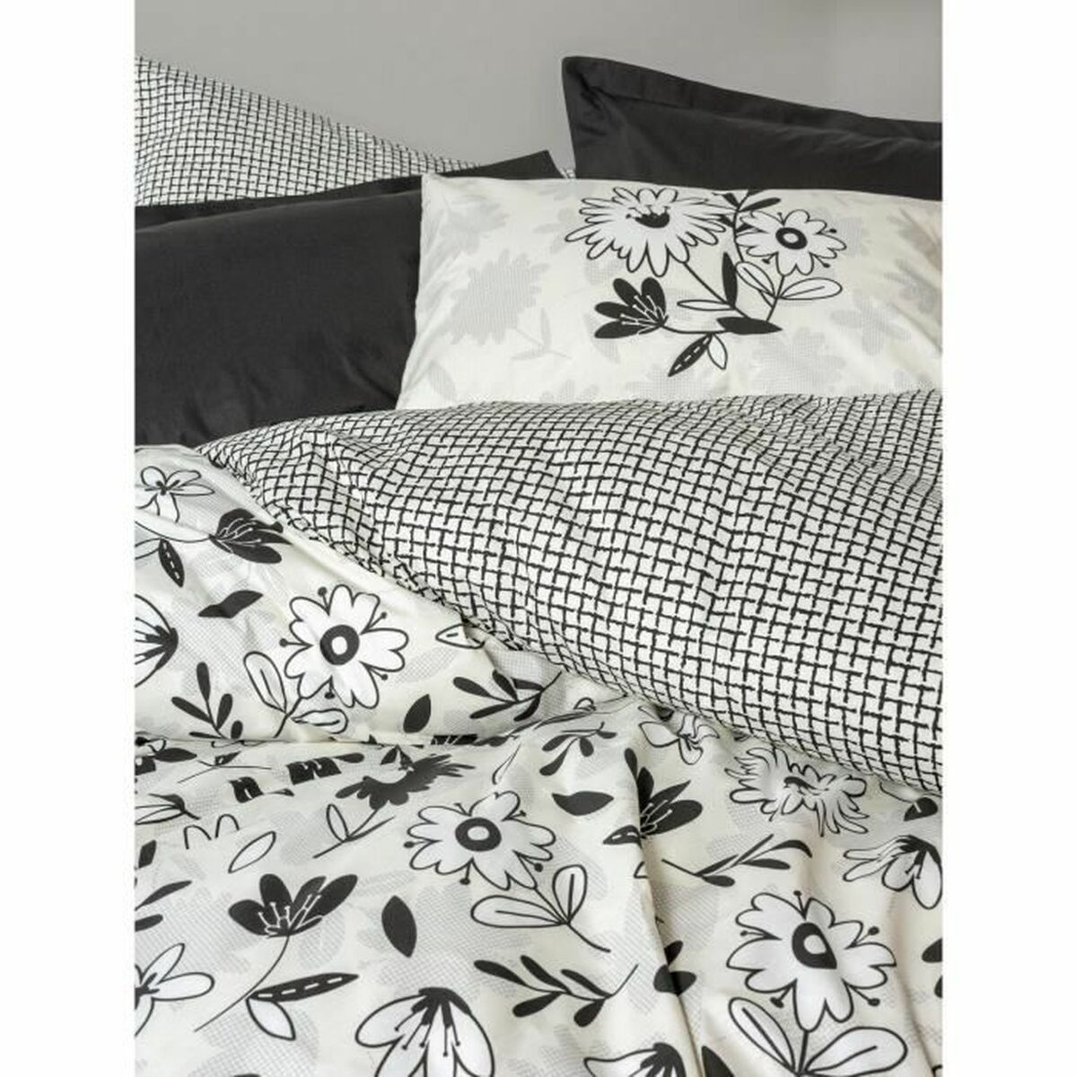 Ein Bett mit floralen Bettlaken und Kissen. Das Muster ist schwarz und weiß.