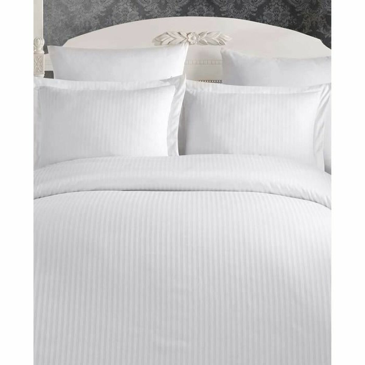 Ein Bett mit weißer gestreifter Bettwäsche. Das Kopfteil ist verziert. Die Bettwäsche ist ordentlich angeordnet.