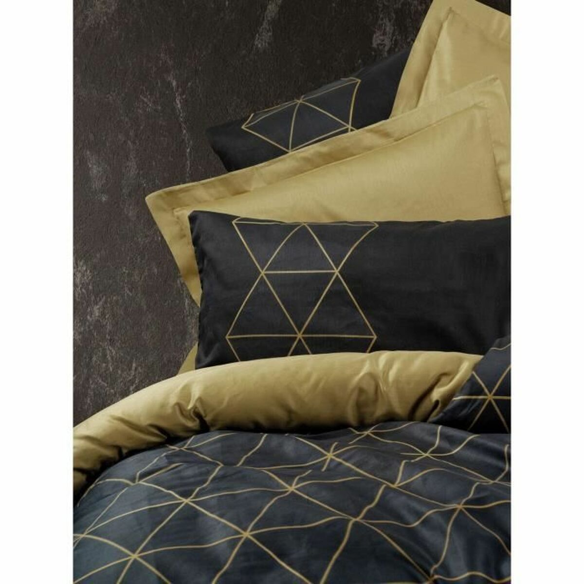 Nahaufnahme eines Bettes mit schwarzer und goldener Bettwäsche. Die Bettdecke hat ein geometrisches Muster.