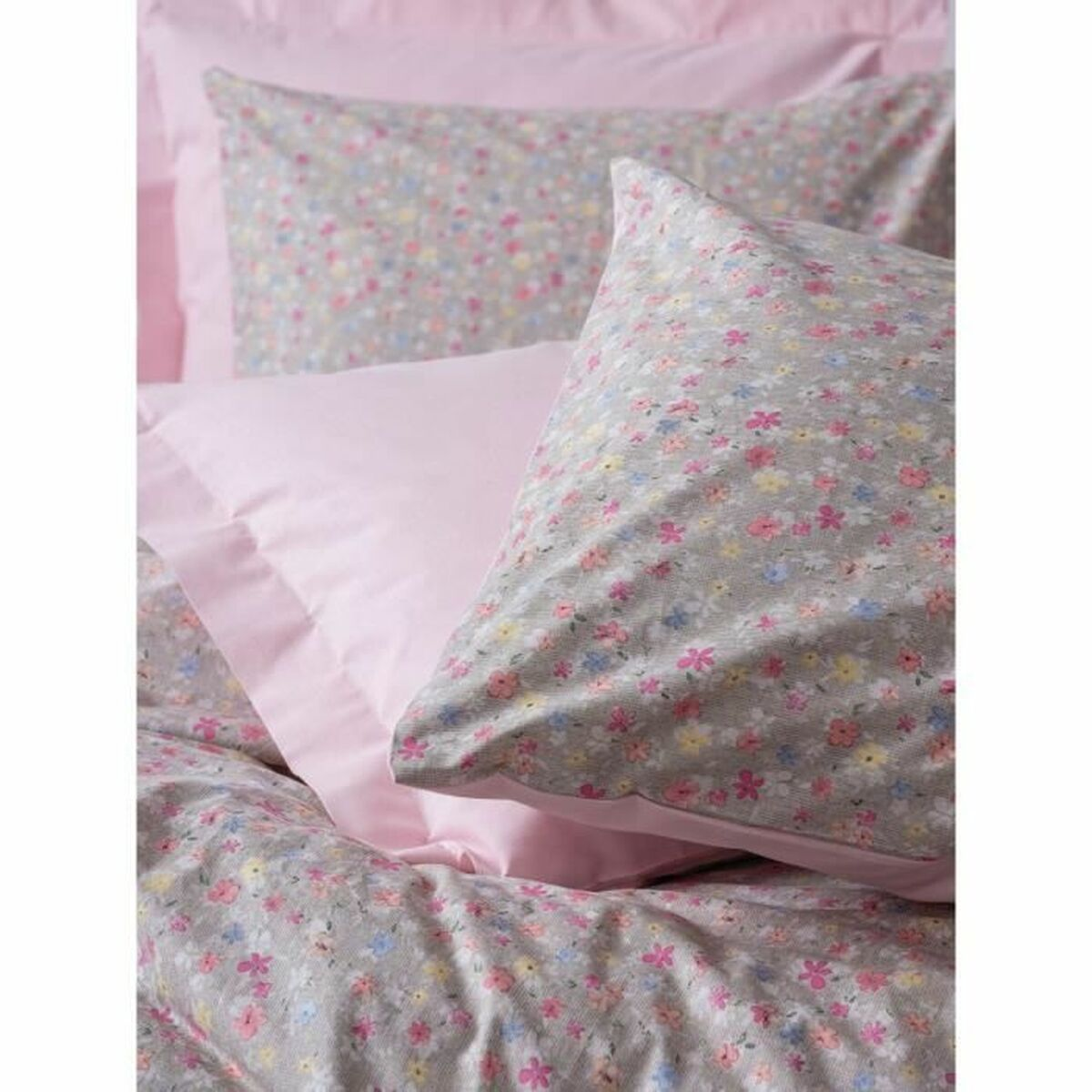 Nahaufnahme von rosa und floralen Kissen und Bettwäsche auf einer Holzoberfläche.