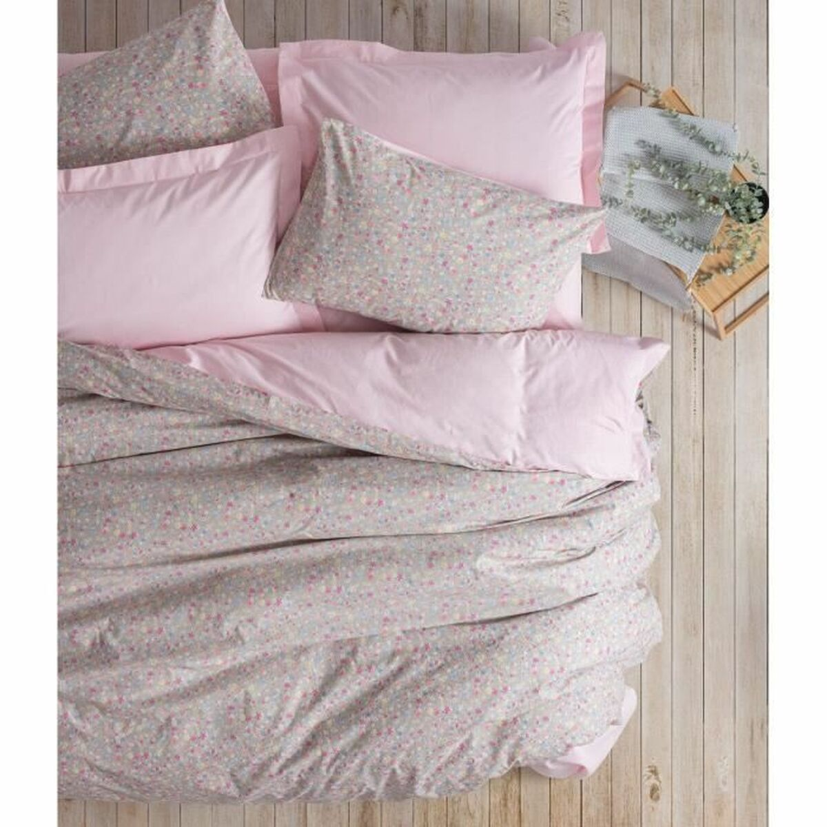 Rosa und blumiges Tagesdecke und Kissen auf Holzoberfläche. Rosa Bettwäsche.