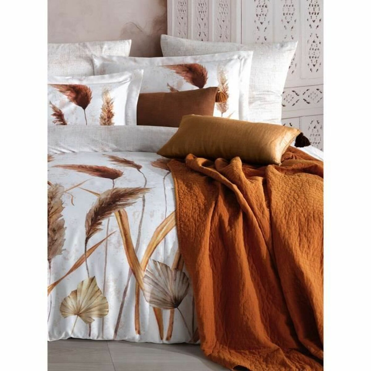 Bettwäsche-Set mit weißem Bettbezug mit braunen Blattmustern, braunen Kissen und einer orangefarbenen Decke.
