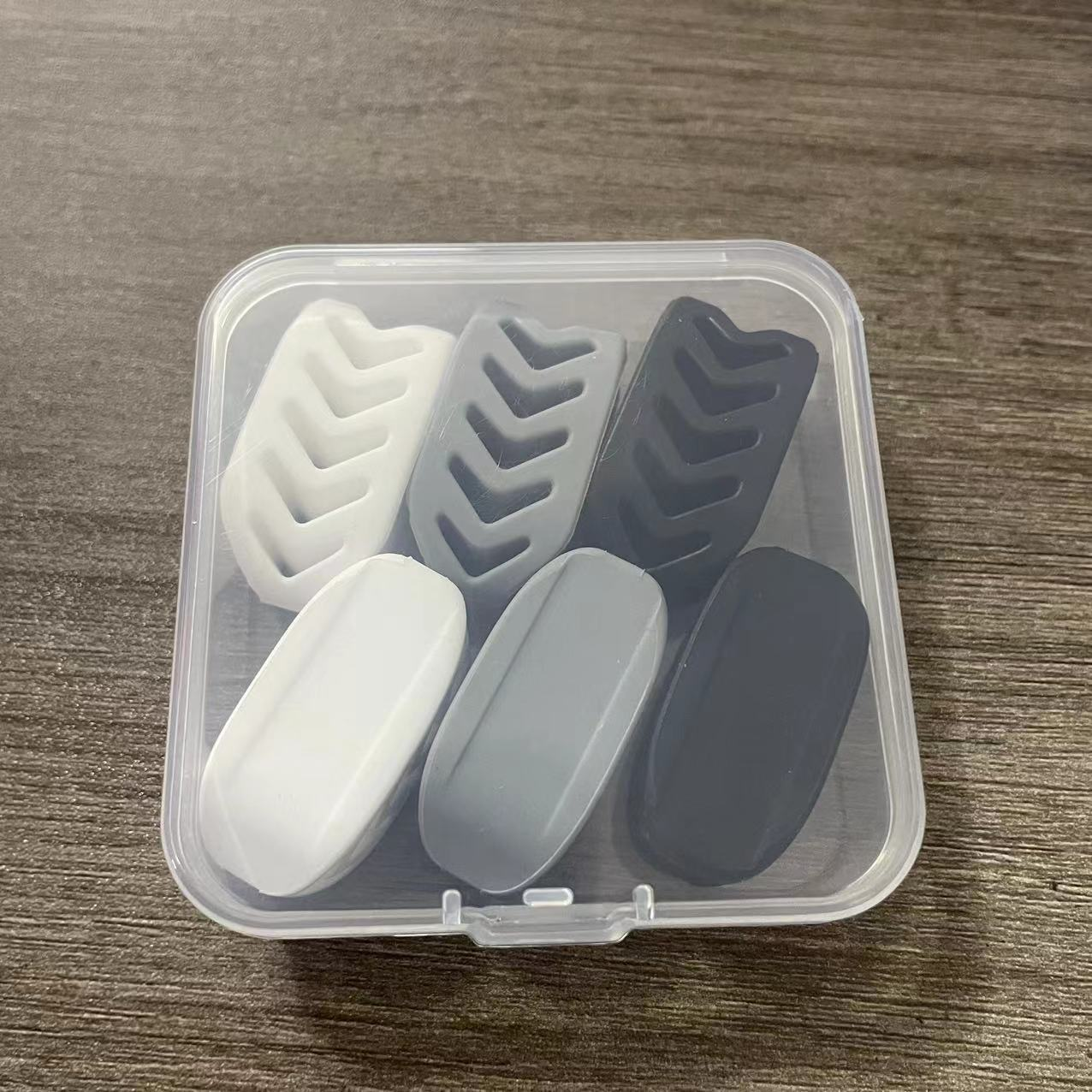 Una custodia di plastica trasparente con sei protezioni dentali grigie e bianche.