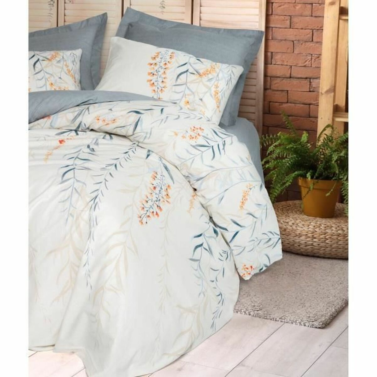 Bett mit weißer Bettwäsche, floralem Design, Kissen und Holzrahmen. Eine grüne Pflanze an der Seite.