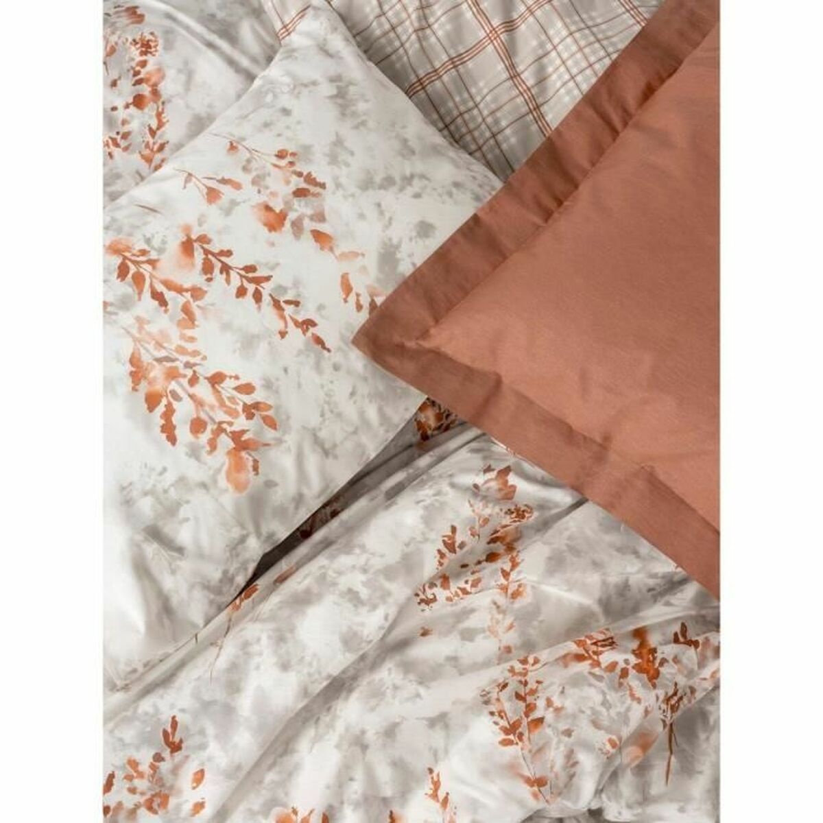 Bettwäsche mit Blumendruck und orangefarbenen Akzentkissen.
